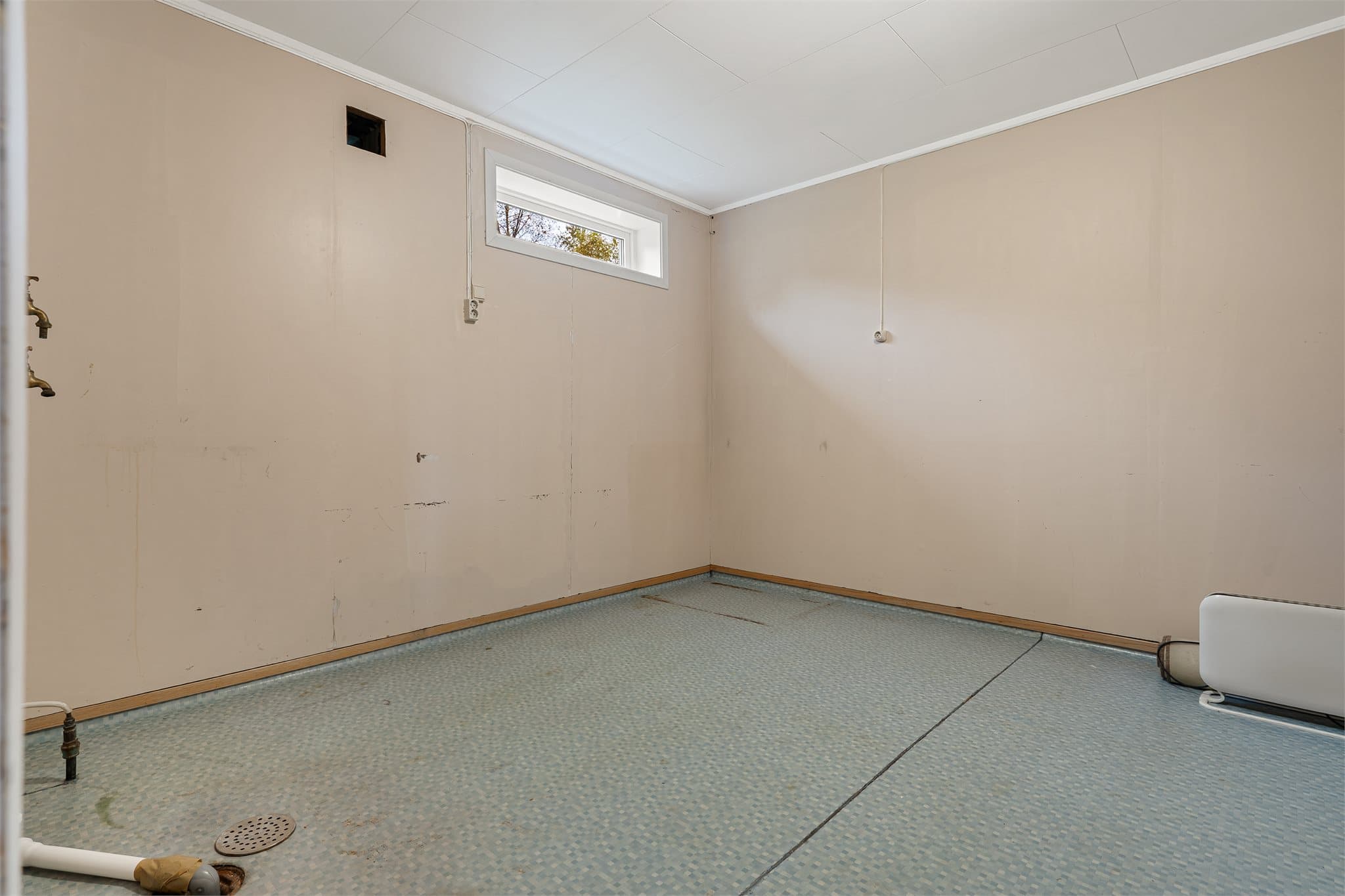 Vaskerom i kjeller med gulvvarme, sluk og opplegg for vaskemaskin.