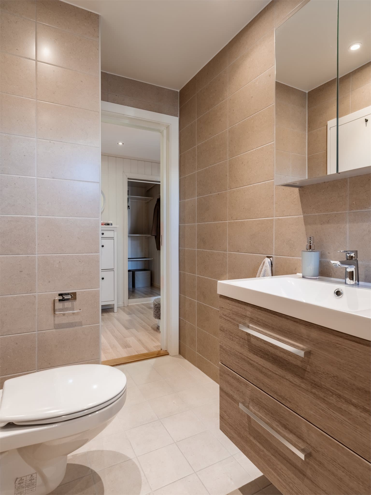 Innredningen inkluderer servant med underskap og vegghengt toalett.