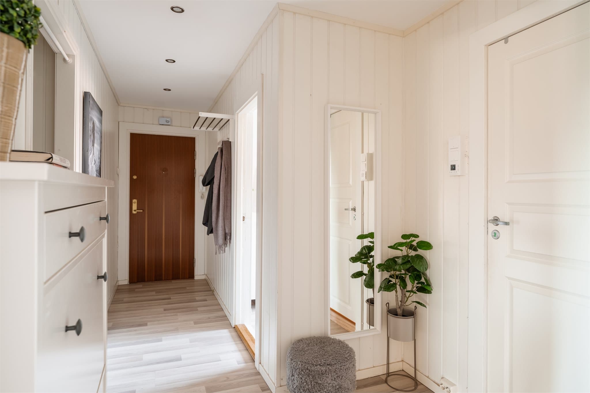 En lys entré med laminatgulv og malte vegger ønsker velkommen inn.