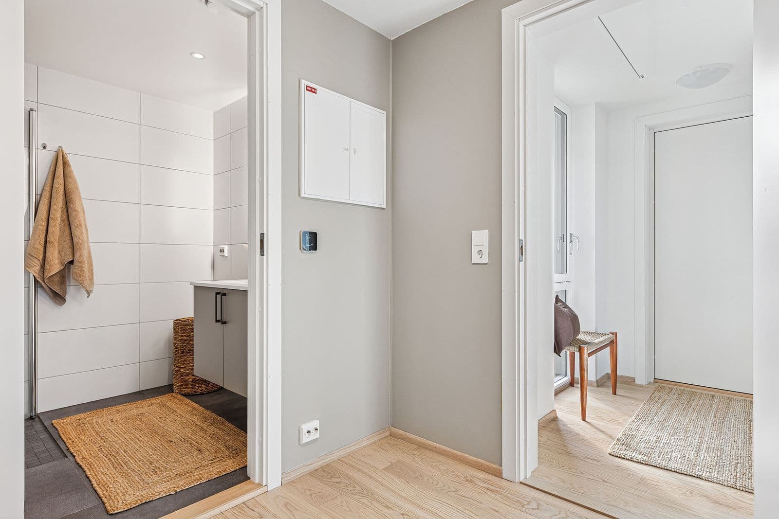 Videre fra badet har man boligens entré. Gjennomgående gulv skaper en helhetlig og sømløs overgang mellom rommene.