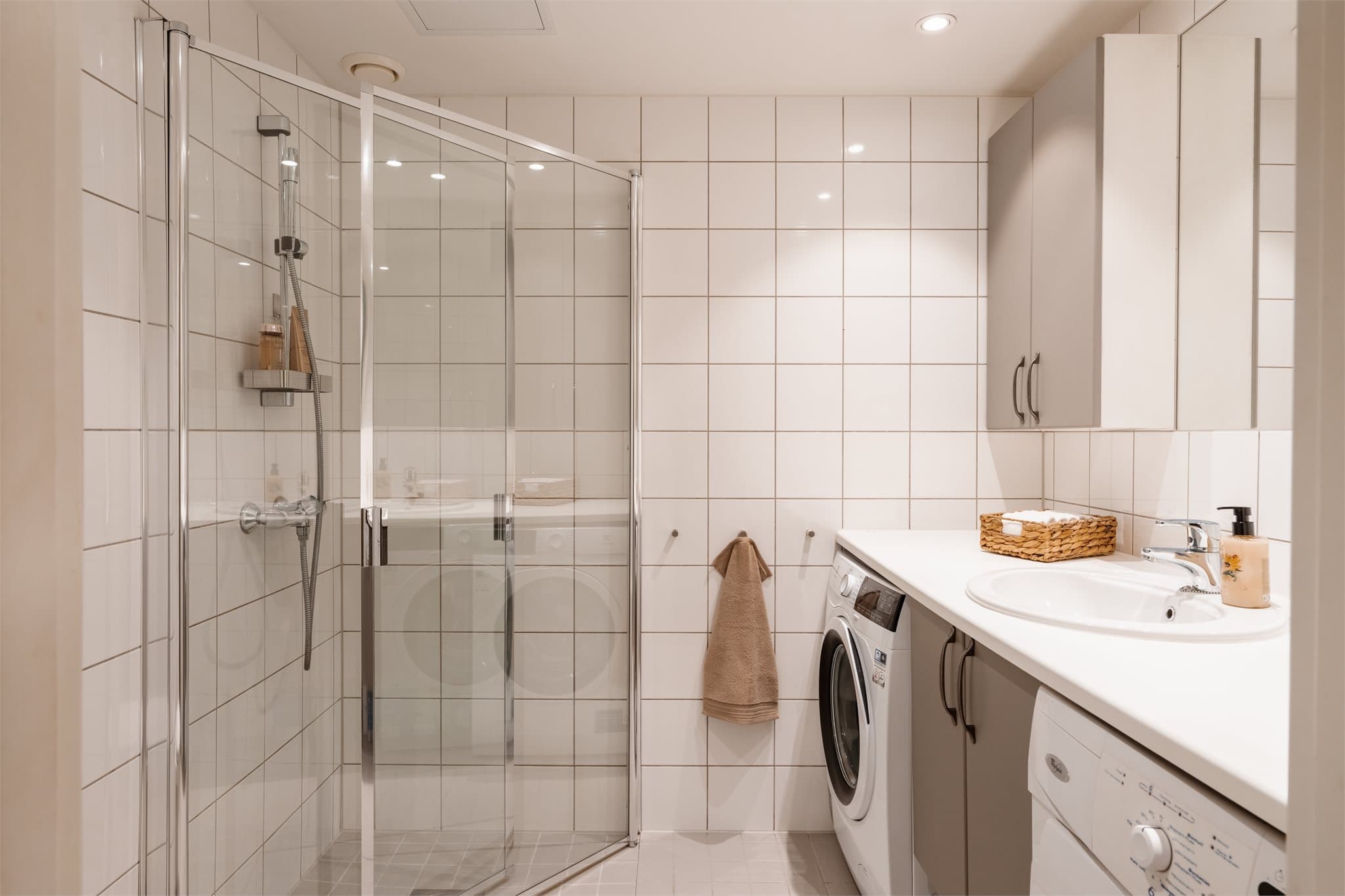 Helfliset bad med dusjhjørne med innfellbare glassdører og opplegg for vaskemaskin.