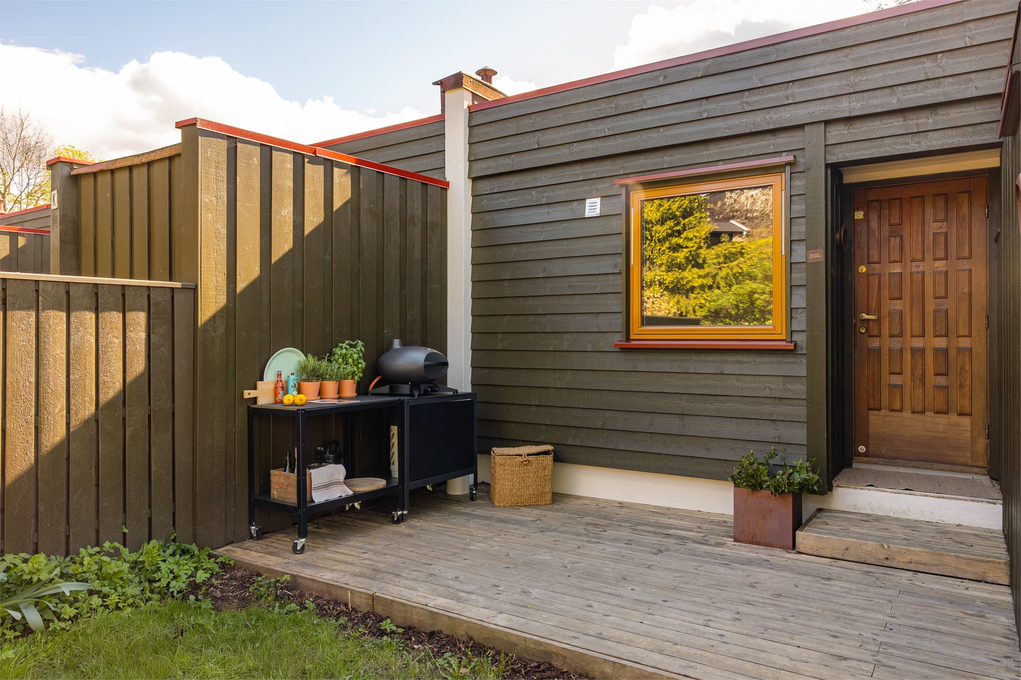 Her er det god plass til utekjøkken for den matglade. Huset i seg selv er malt i en fin og varm olivenfarge med inngangsdør i tre, lekre detaljer.