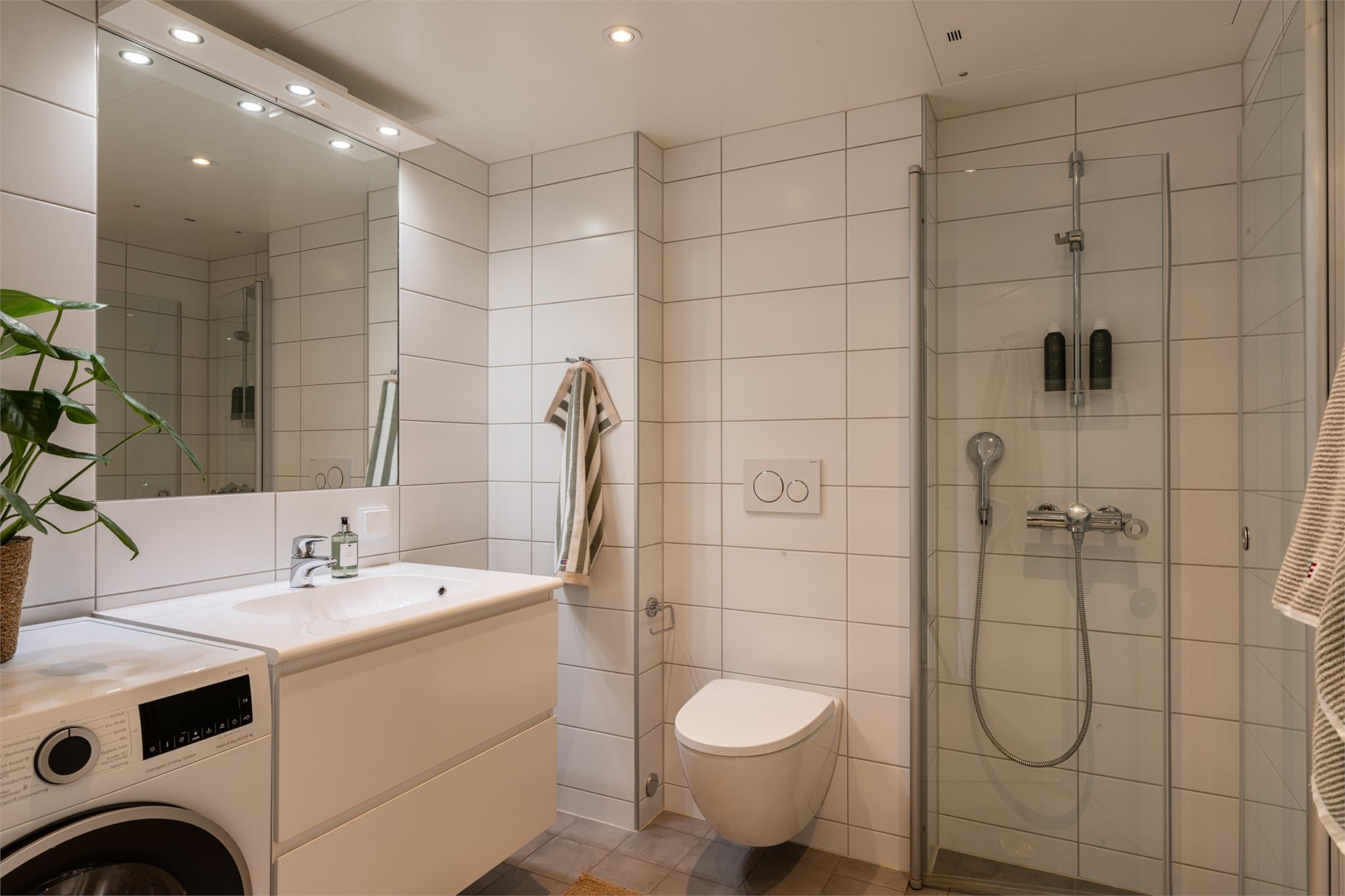 Badet er et moderne, prefabrikkert bad med flislagte overflater og behagelig vannbåren gulvvarme.