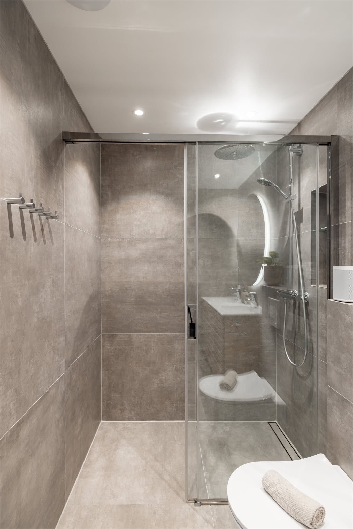 Dusjsonen er en nedsenket nisje med skyvedør i glass og moderne slukrenne.