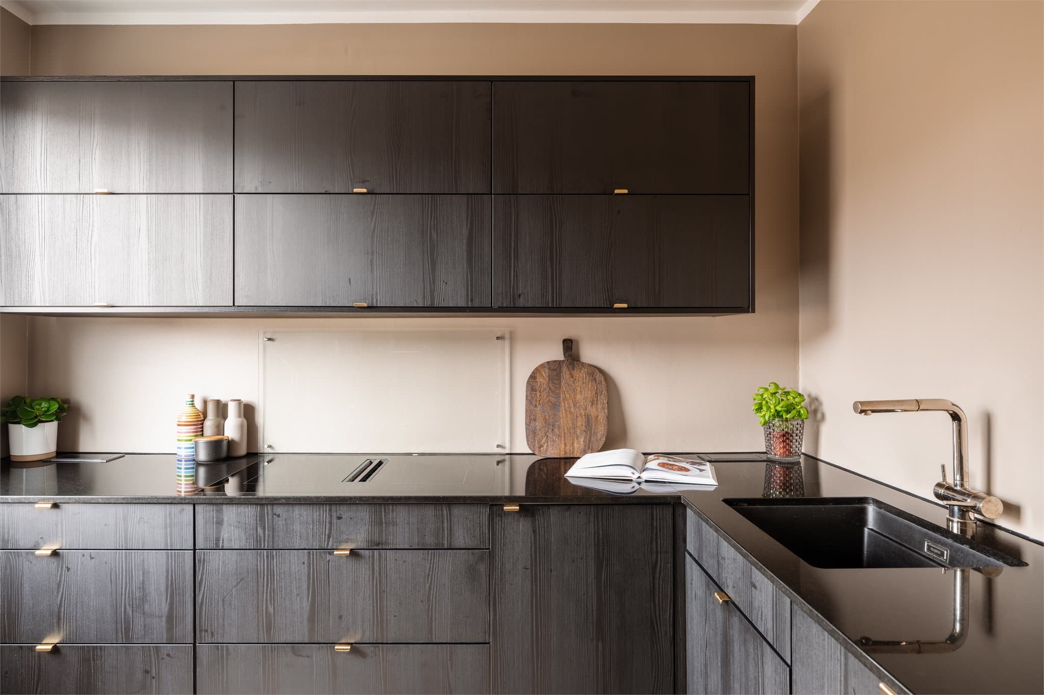 Kjøkkenet er utstyrt med en påkostet kjøkkenbenk fra Nerostein (granitt) Nero Assoluto, innfelt platetopp med nedtrekk kullfilter og innfelt vask med italiensk gullservant.