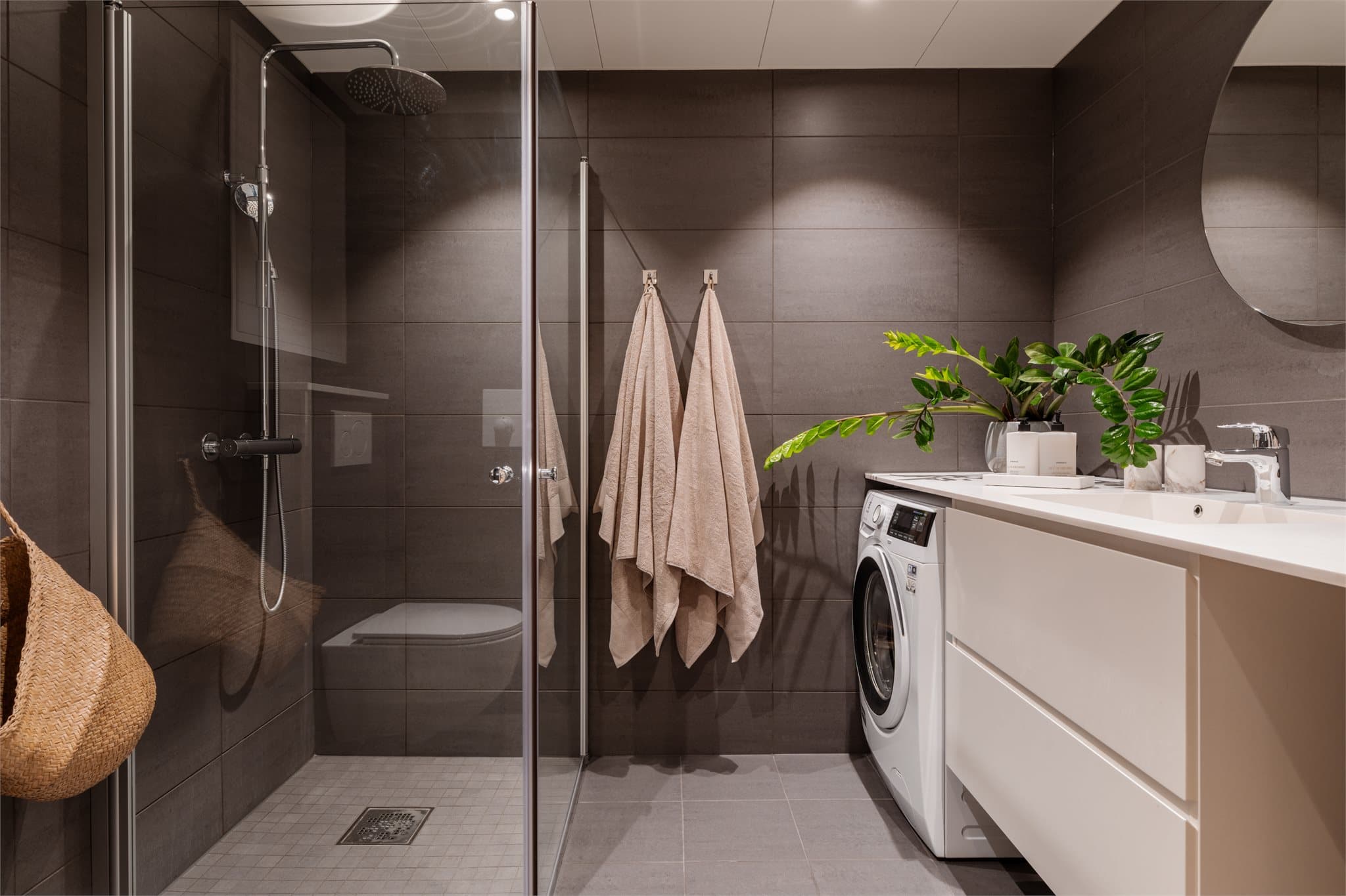 Lekkert baderom med mørke fliser og lys innredning.