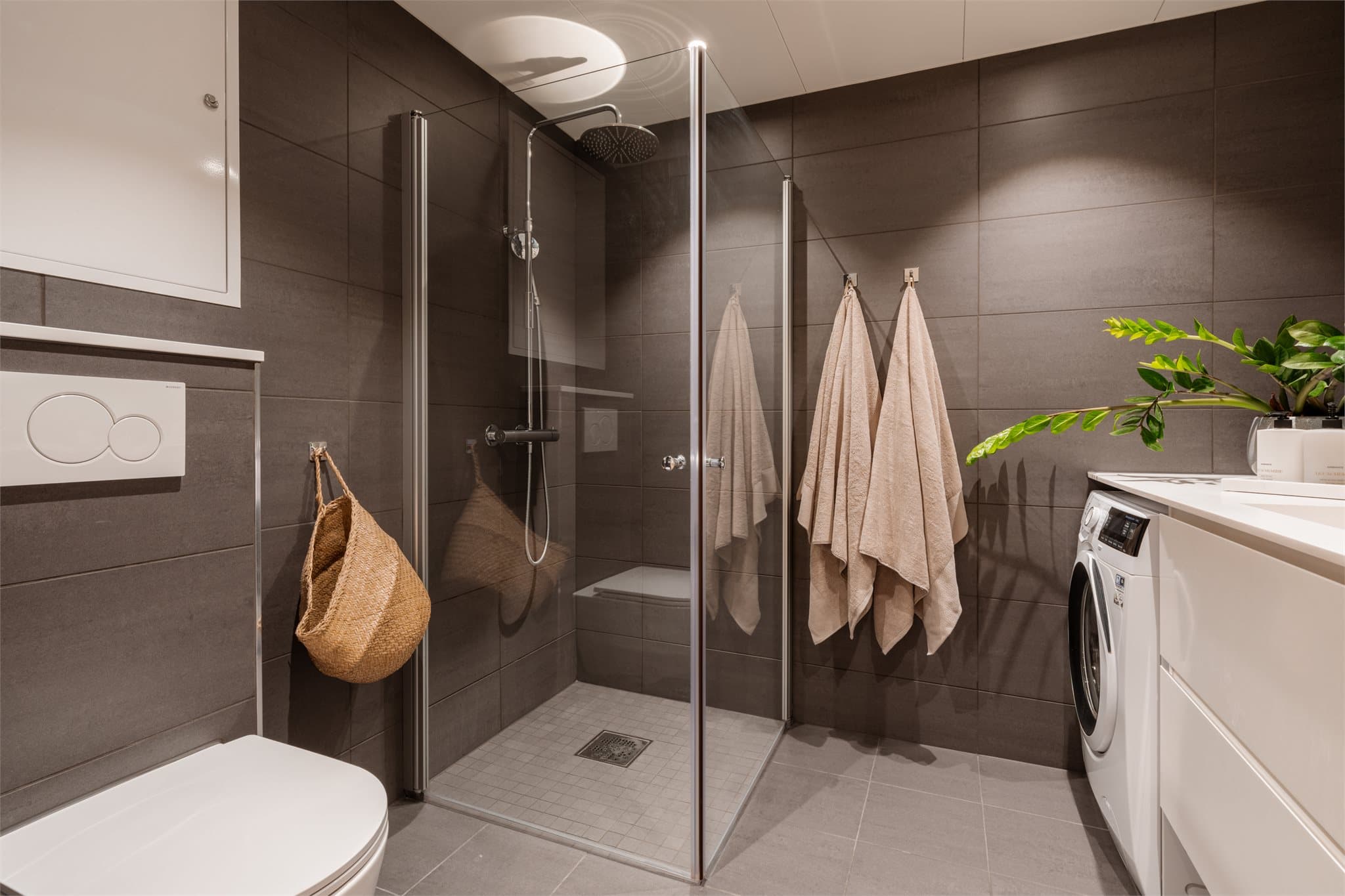 Videre har badet en romslig dusjnisje med regnfallsdusj og innfellbare glassdører.