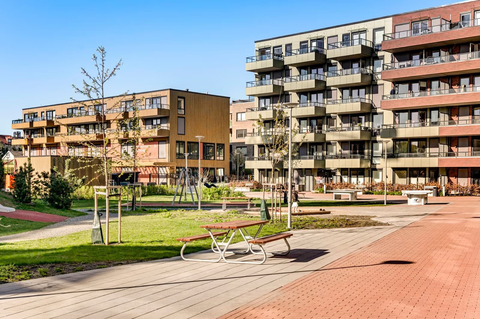 Innbydende fellesområder med sittegrupper, lekeplasser og grønne omgivelser.