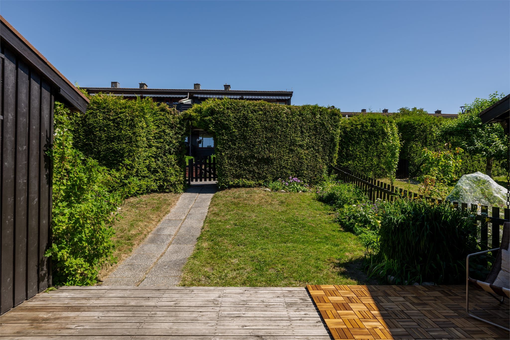 Adkomsten til boligen skjer via en skjermet hage med hekk og heller frem til en hyggelig terrasse på 23m² ved inngangspartiet.