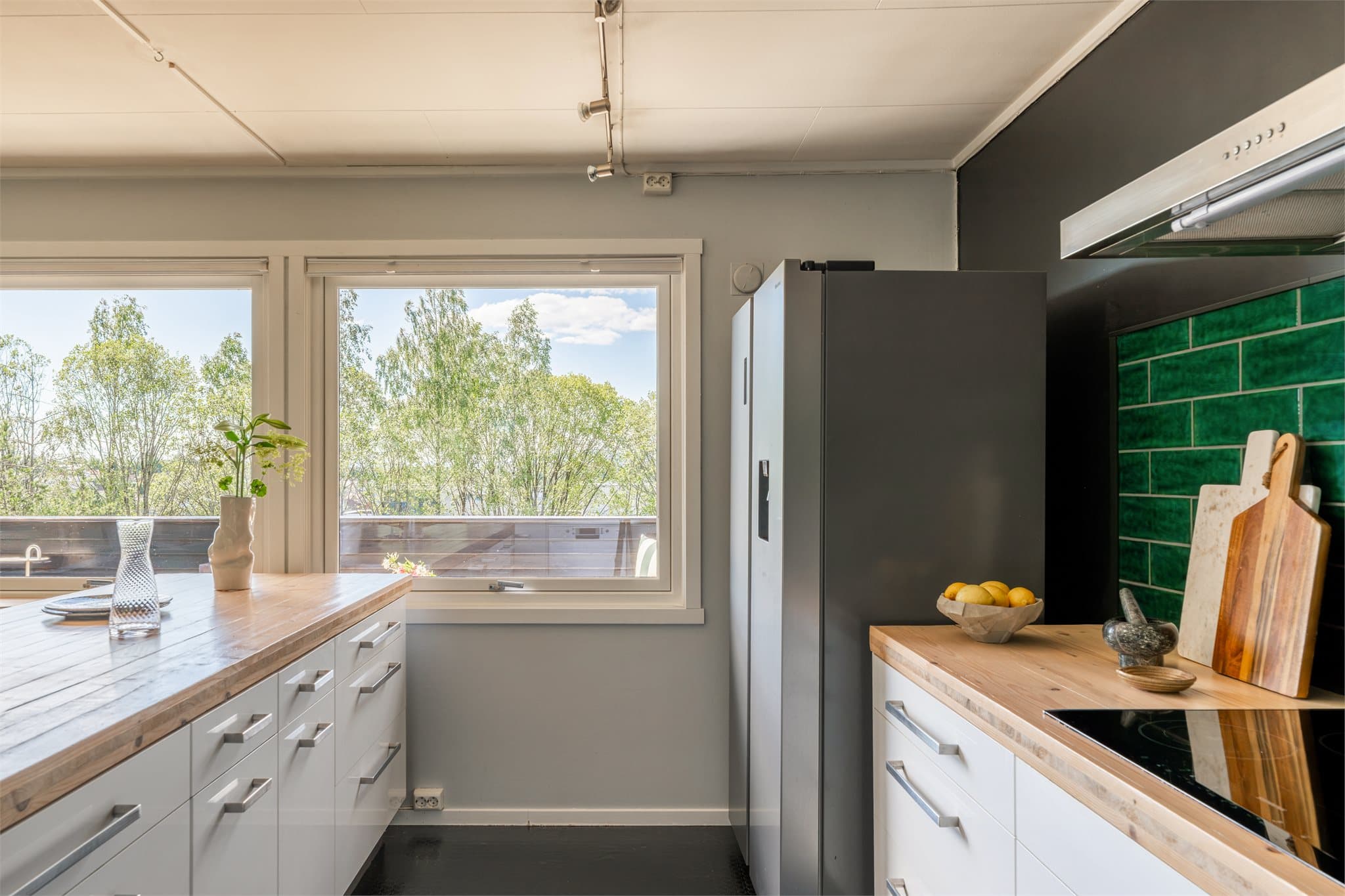 Innredningen består av hvite høyglansfronter fra Ikea, kombinert med benkeplate i heltre og flislagt vegg over benken, utført i løpet av de siste fem årene.