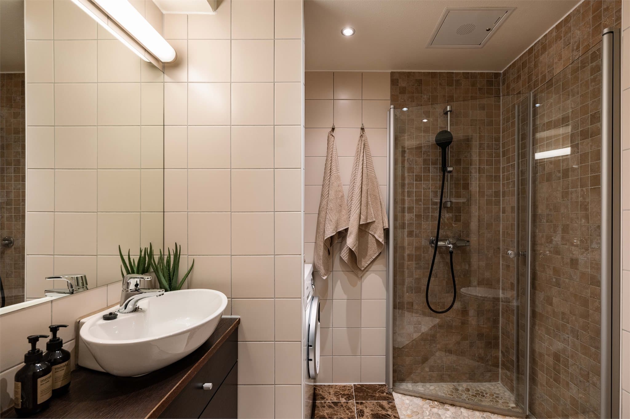 Flislagt bad fra 2010 med vegghengt toalett, dusjhjørne og opplegg for vaskemaskin.