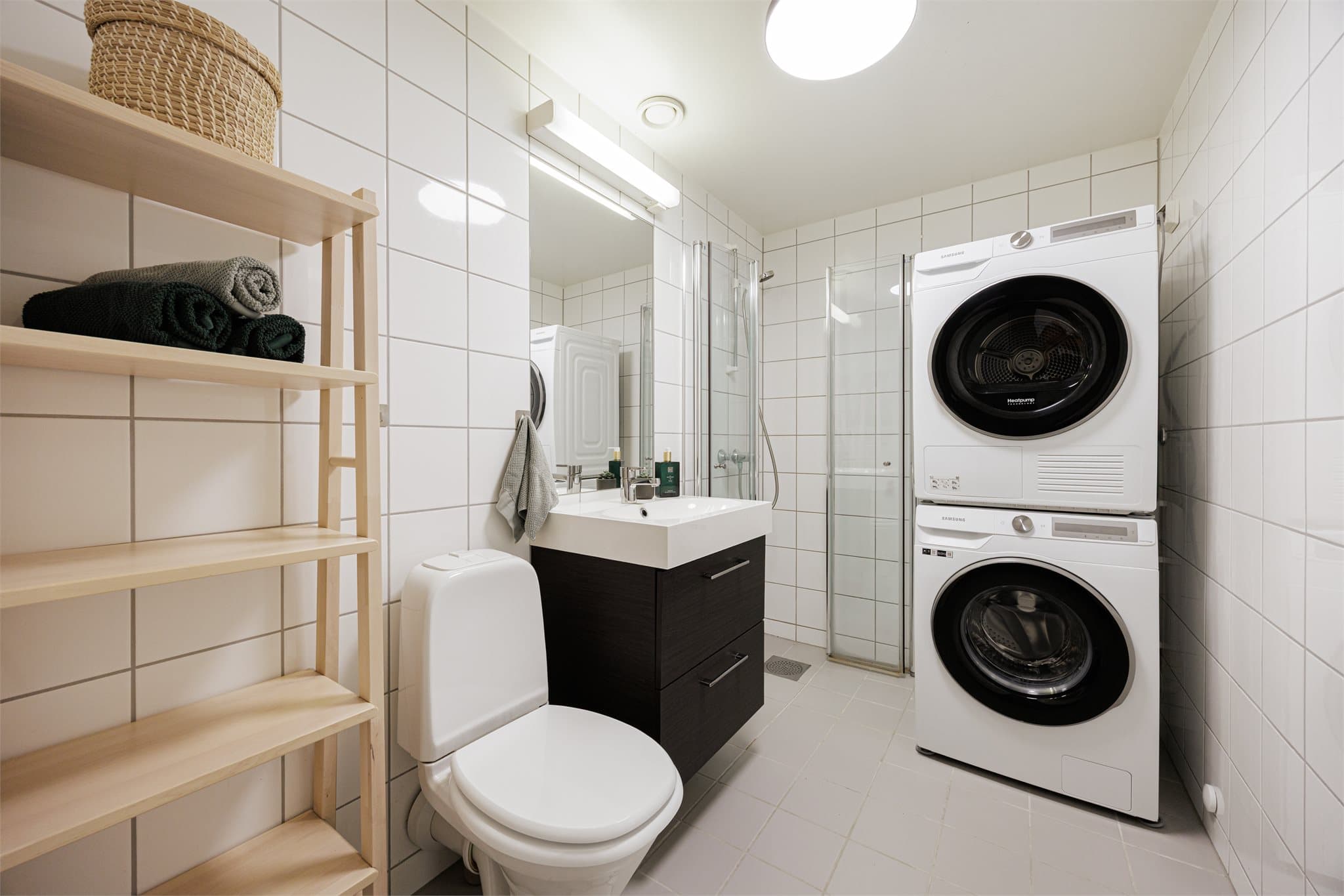 Flislagt og funksjonelt baderom med gulvvarme for ekstra komfort. Badet er innredet med benkeskap med glatte fronter og heldekkende servant, samt innfliset speil over.