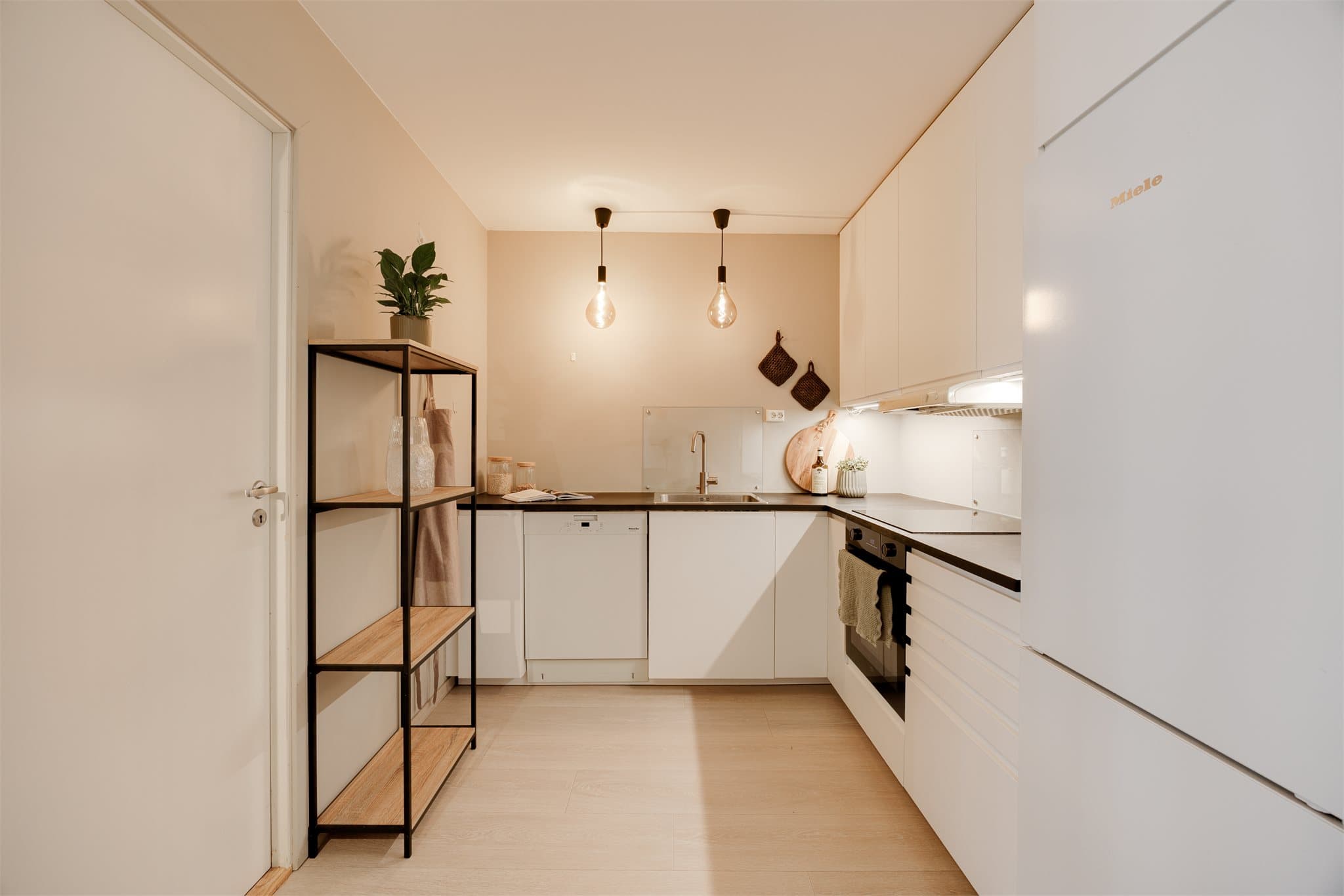 Over platetopp og kum er det montert glassplate som både beskytter veggen og gir et tidsriktig uttrykk. Innredningen har god skap- og benkeplass, nedfelt kum i rustfritt stål og ventilator.