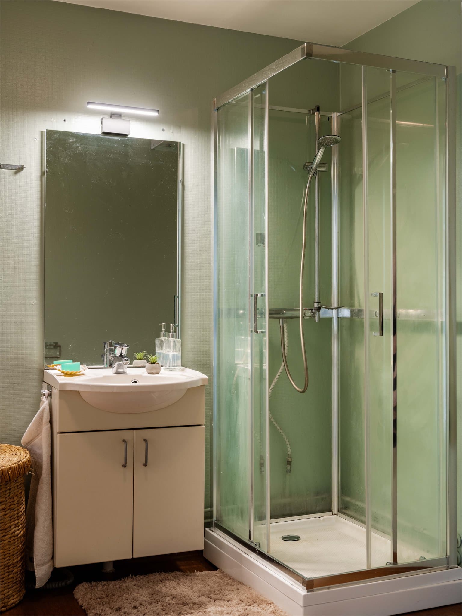 Badet har dusjkabinett og servant med underskap.