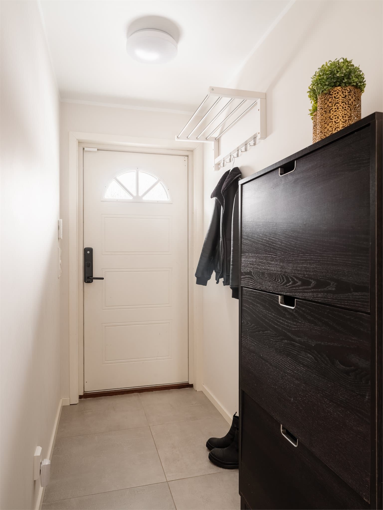 Velkommen inn i en lys entré med flislagt gulv og plass til yttertøy.