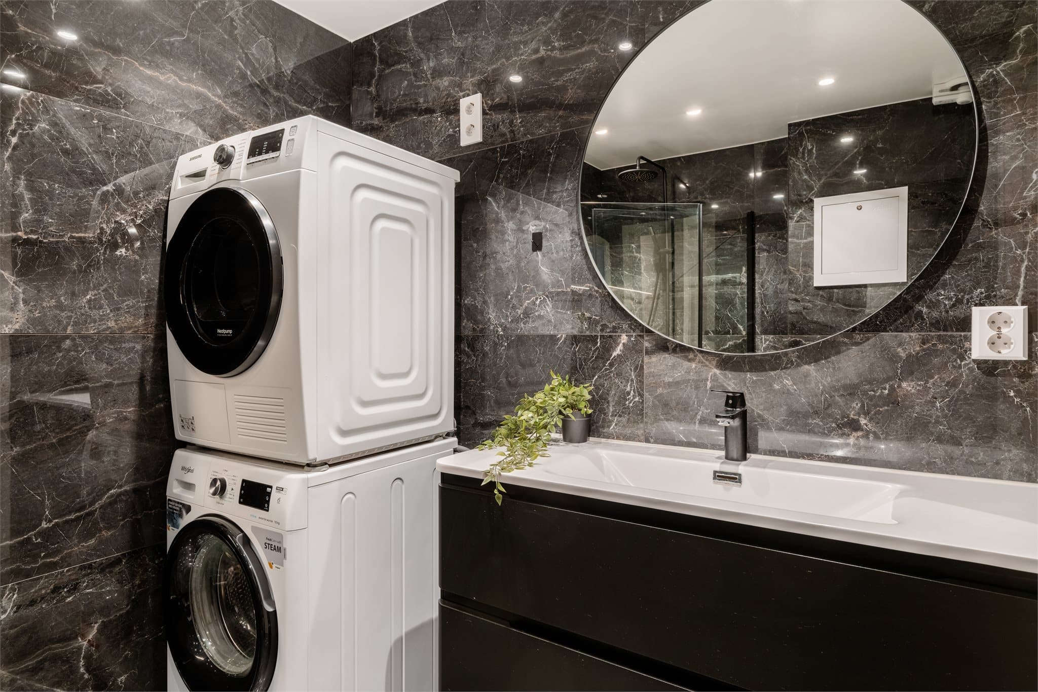 Badet har en stilren innredning med servant og praktisk opplegg for vaskemaskin.