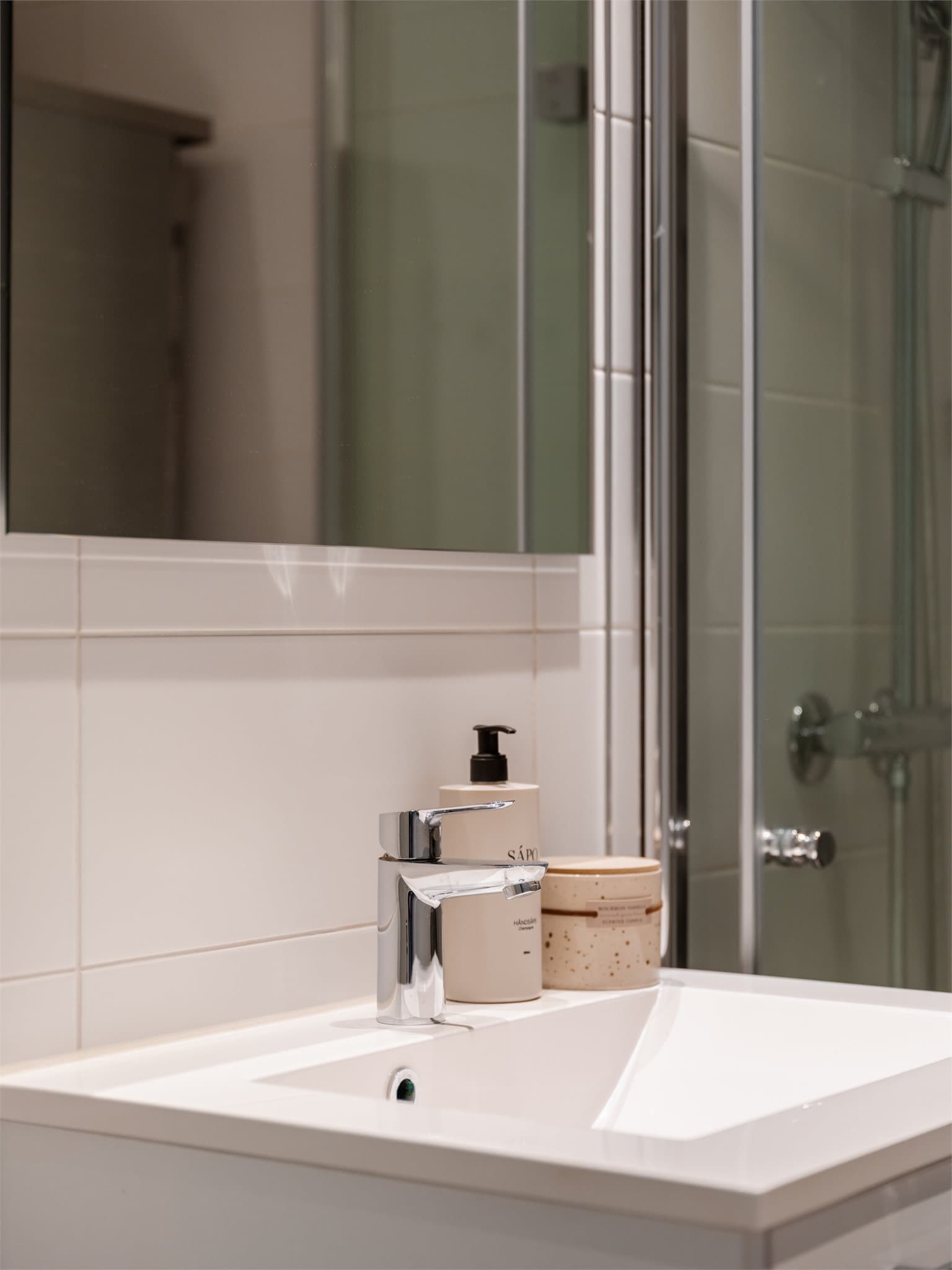 Badet har stilren baderomsinnredning med heldekkende servant og oppbevaringsplass.