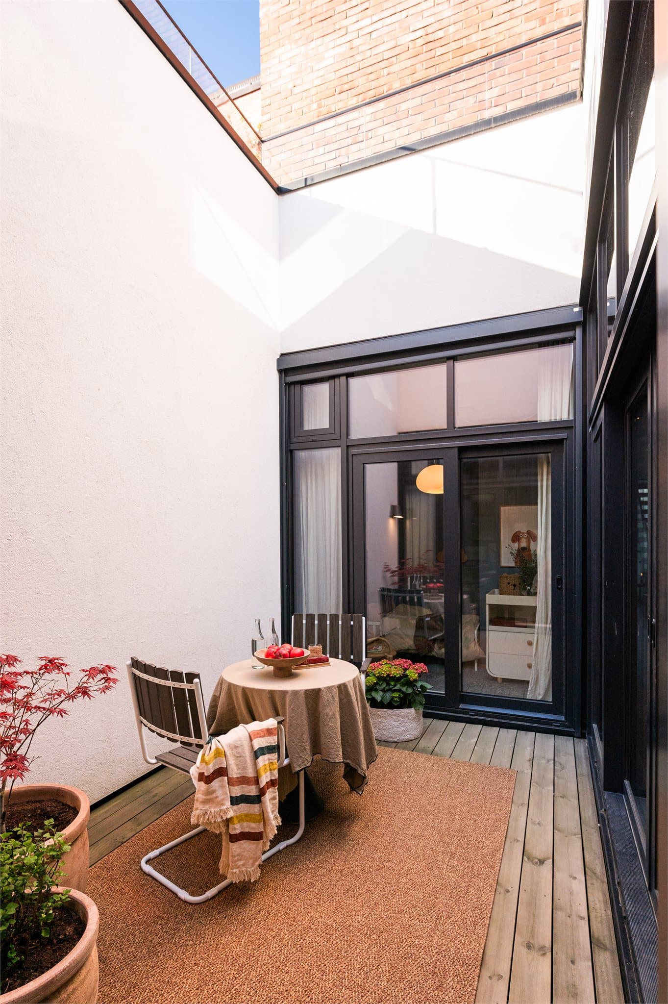 Atriet har terrassebord i tre og er møblert med en hyggelig sittegruppe og dekorative plantekasser som gir en varm og innbydende stemning.