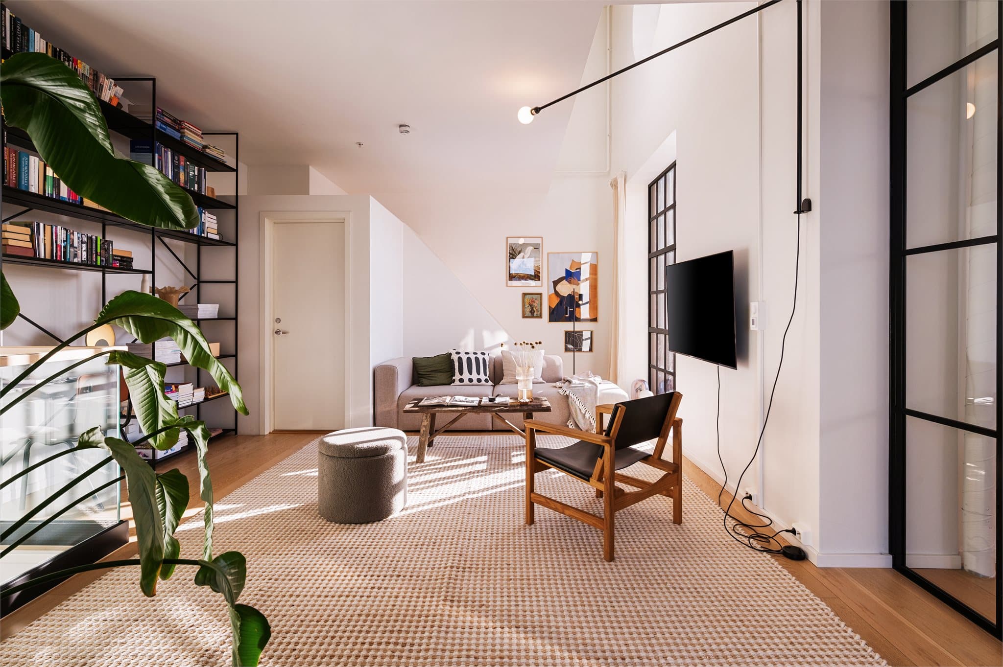 En del av stuen er avdelt og innredet som et romslig soverom, elegant skjermet med sorte glassdører.