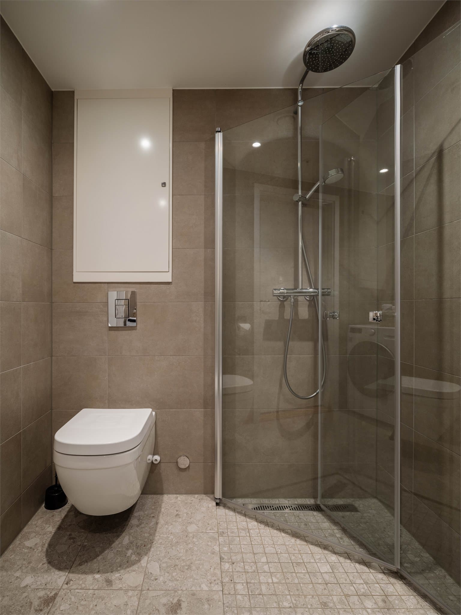 Videre har badet en romslig dusjplass bak innfellbare dører i herdet glass.