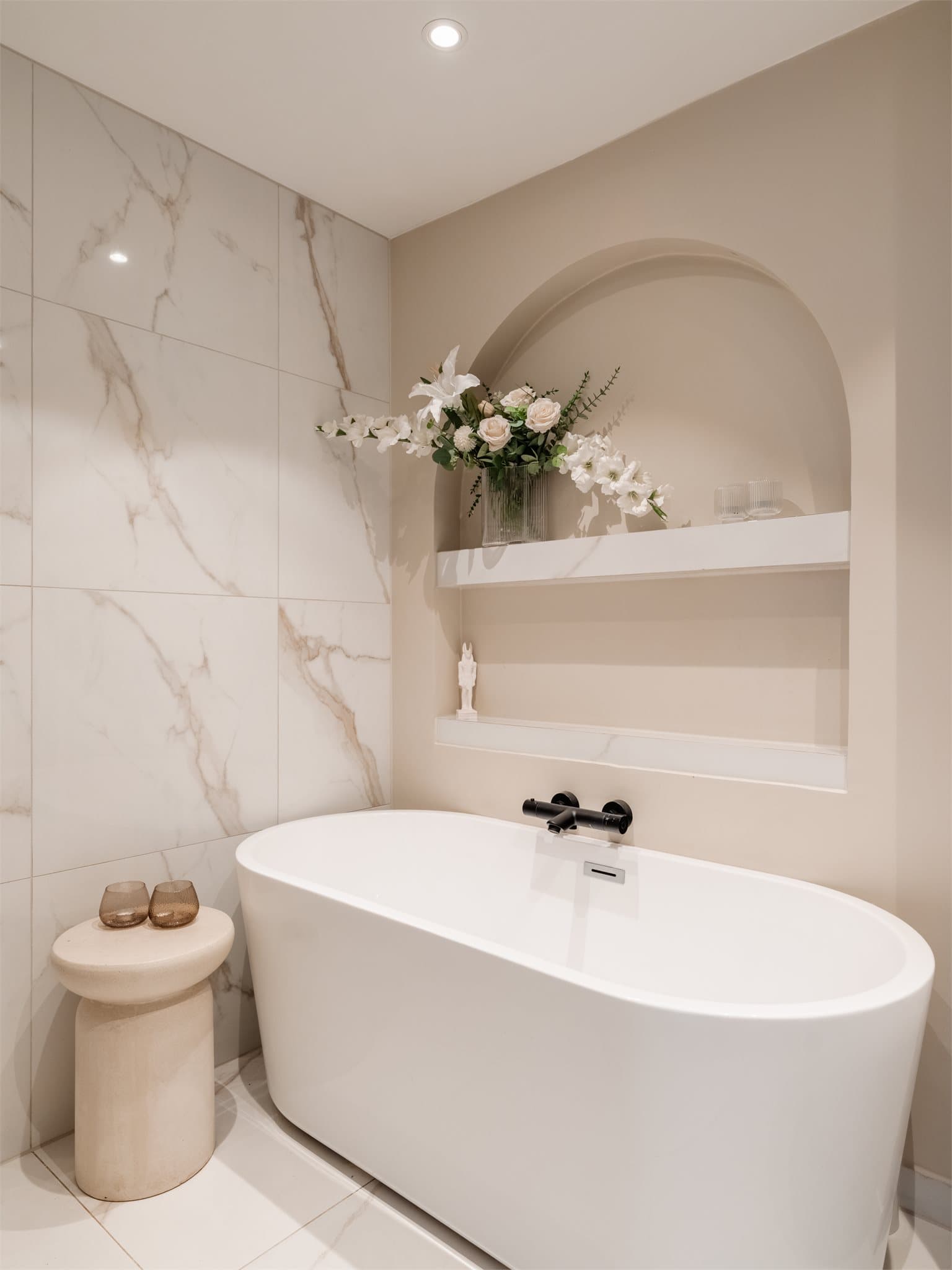 Delikate, innebygde nisjer og et frittstående badekar gir badet et elegant preg.