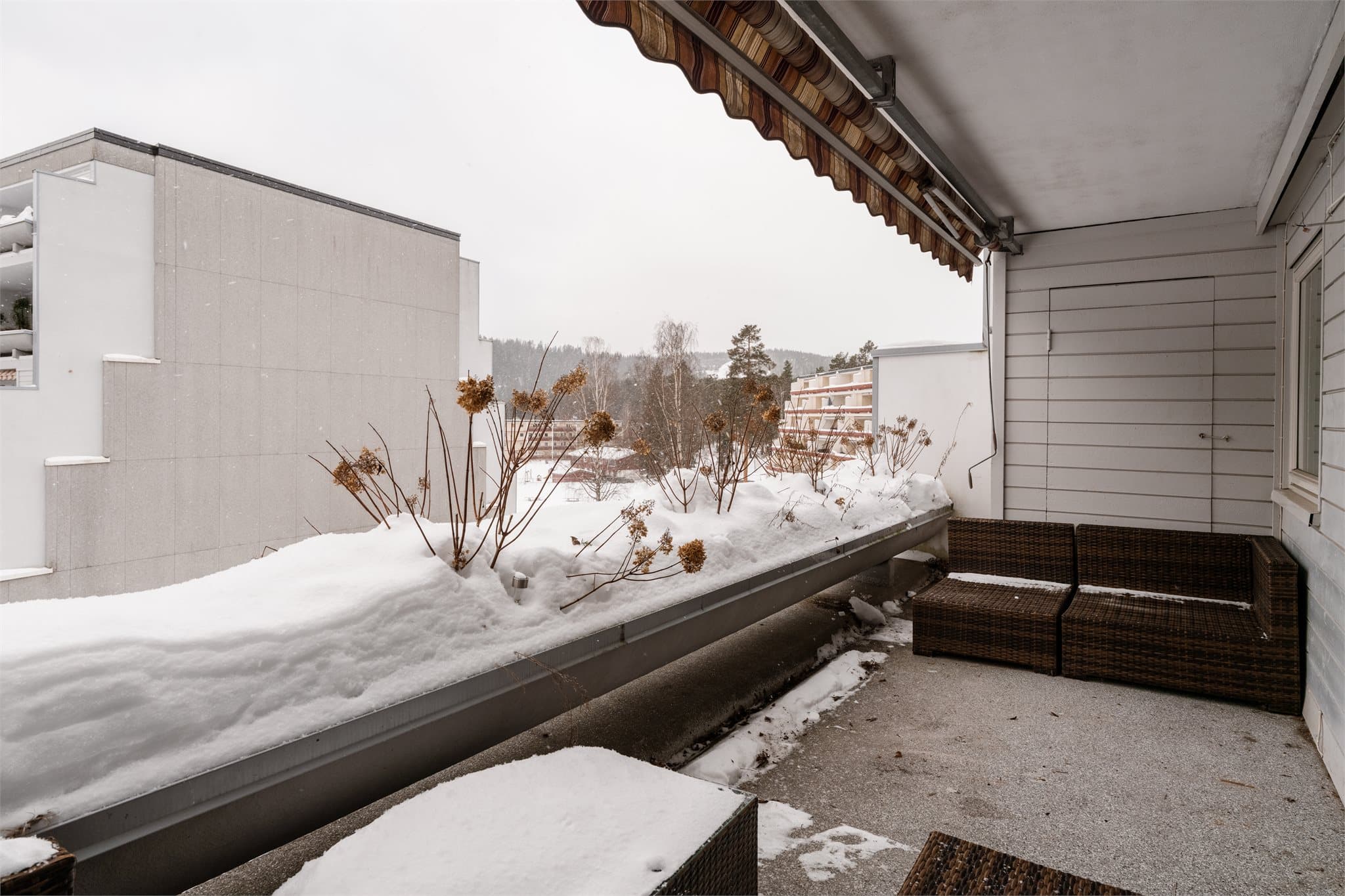 Balkongen har overbygg og markise, samt støpte blomsterkasser for et frodig uttrykk.