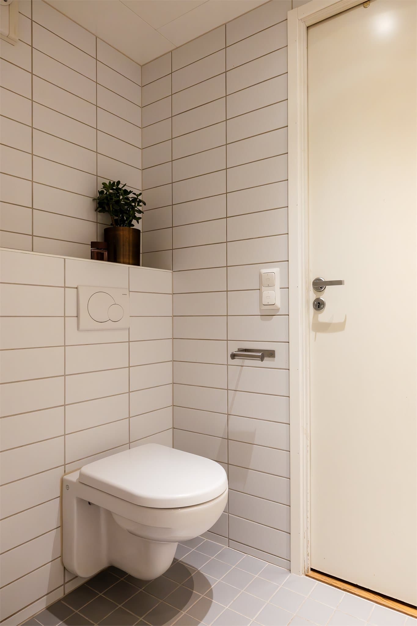 Toalettet er vegghengt og med en praktisk hylle for baderomsartikler og pynt.