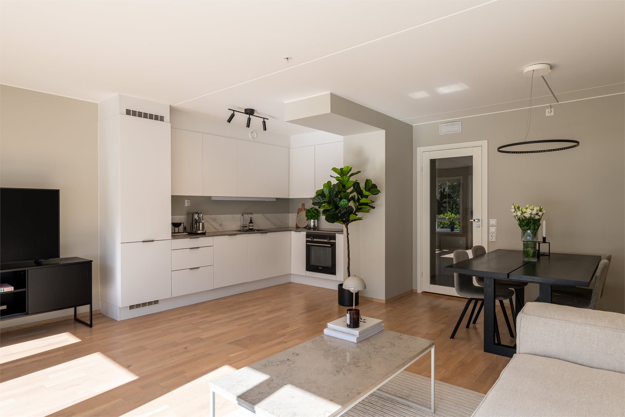 Kjøkkenet er levert av Sigdal og har et tidløst design med glatte, hvite fronter og laminat benkeplate med nedfelt vask. Kjøkkenet oppgradert med steinplate som backsplash.
