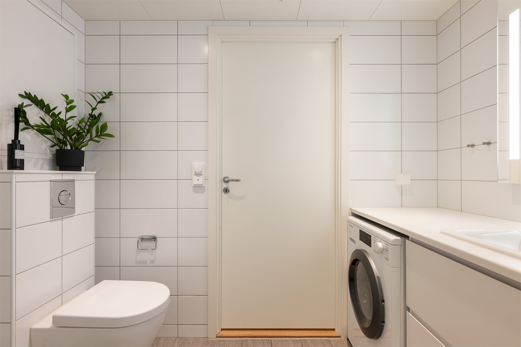 Badet har vegghengt toalett og opplegg for vaskemaskin.