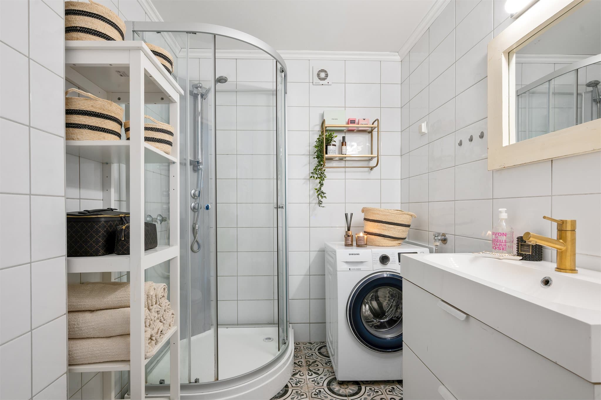 Praktisk og innbydende baderom med god plass til vaskemaskin, moderne innredning og dekorative gulvfliser som skaper et eksklusivt uttrykk.