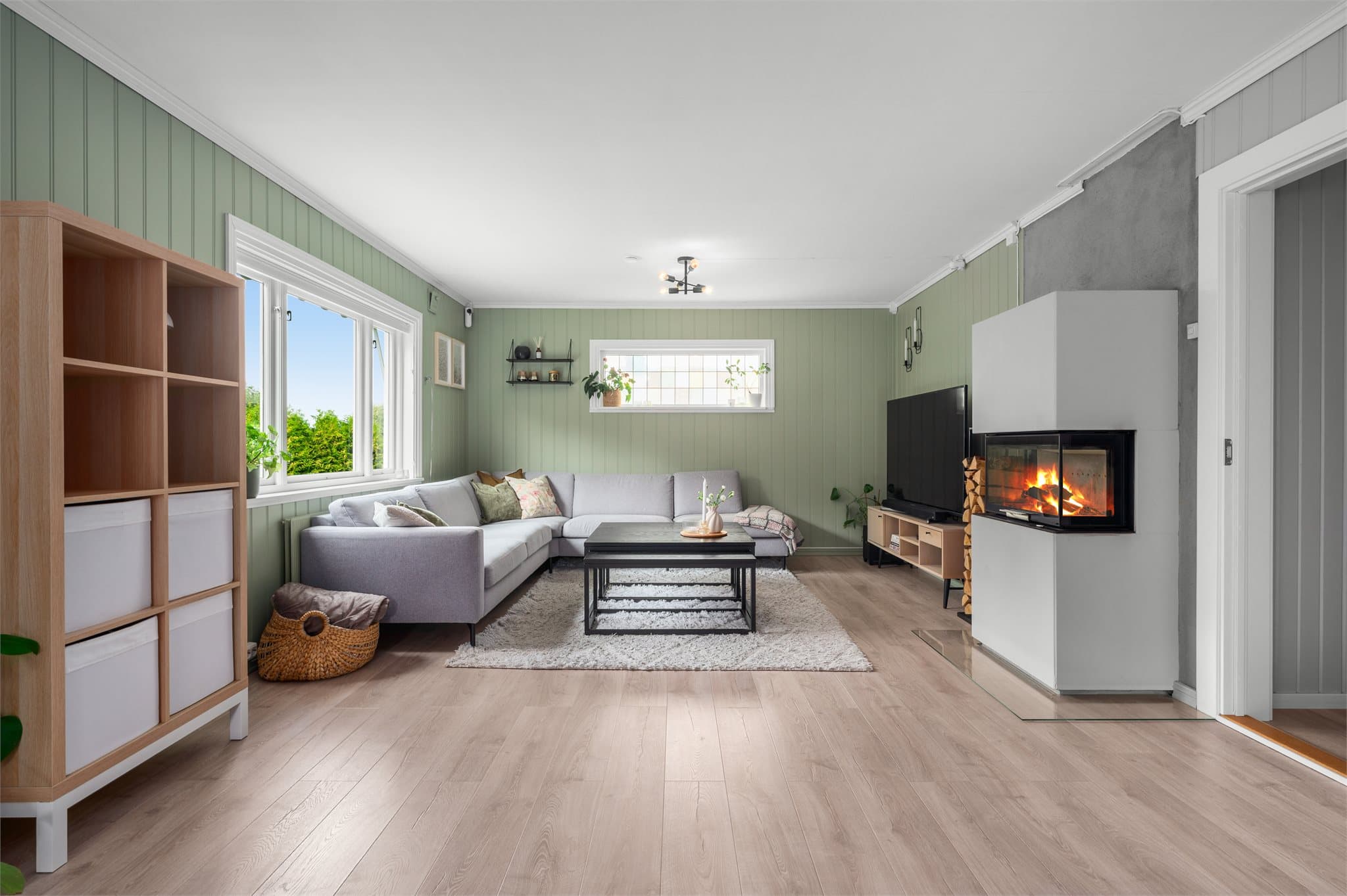 Stuen har en hyggelig atmosfære og fungerer som et naturlig samlingspunkt i boligen.