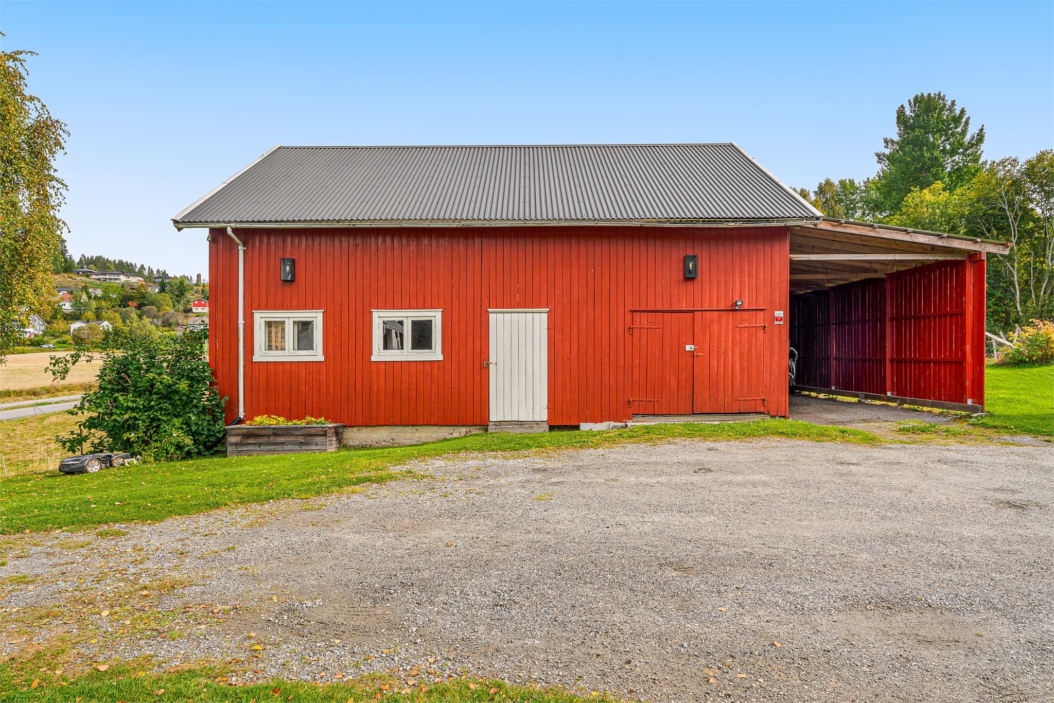 Låven/uthuset har både carport og garasje med plass til en liten bil.