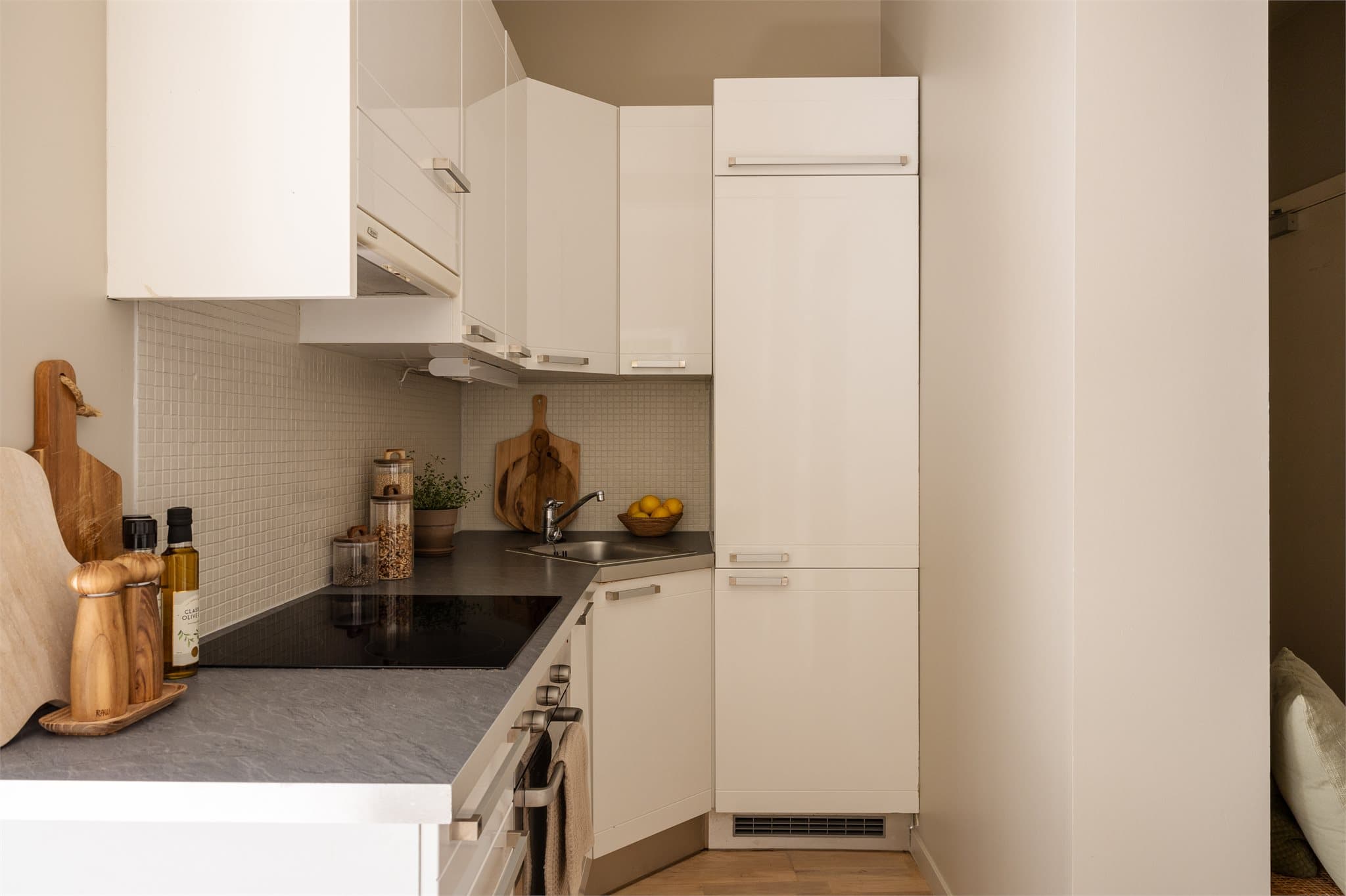 Kjøkkeninnredning med glatte fronter, laminatbenkeplate og integrerte hvitevarer som medfølger salget.