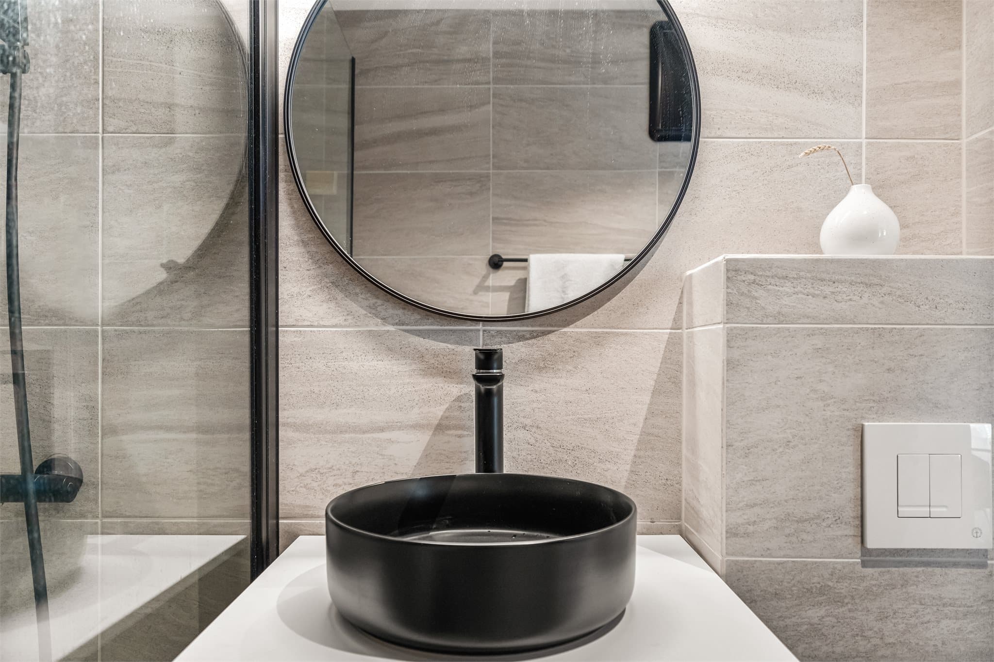 Store fliser på gulv og vegger gir et elegant uttrykk, mens sorte detaljer skaper en stilren kontrast.