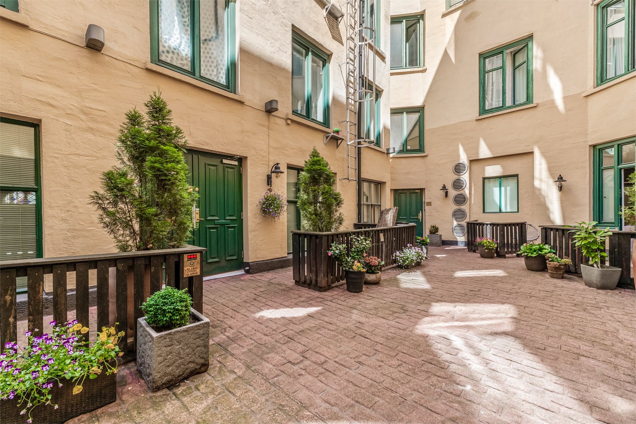 Hyggelig og skjermet felles bakgård med beplantning og sitteplasser.