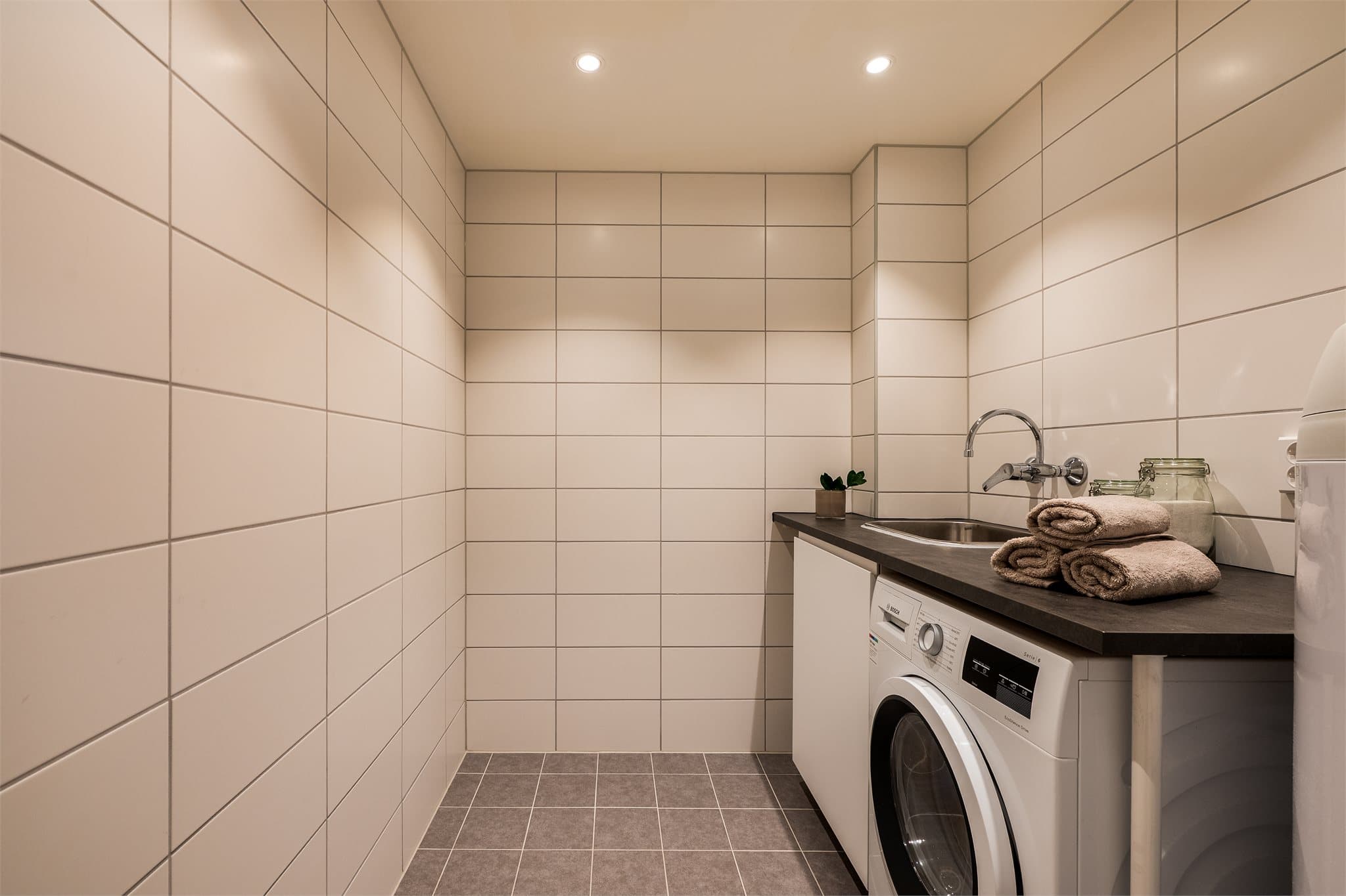 Praktisk vaskerom med gulv- og veggfliser, pusset opp i regi av borettslaget i 2021–2022. Rommet har opplegg for vaskemaskin.