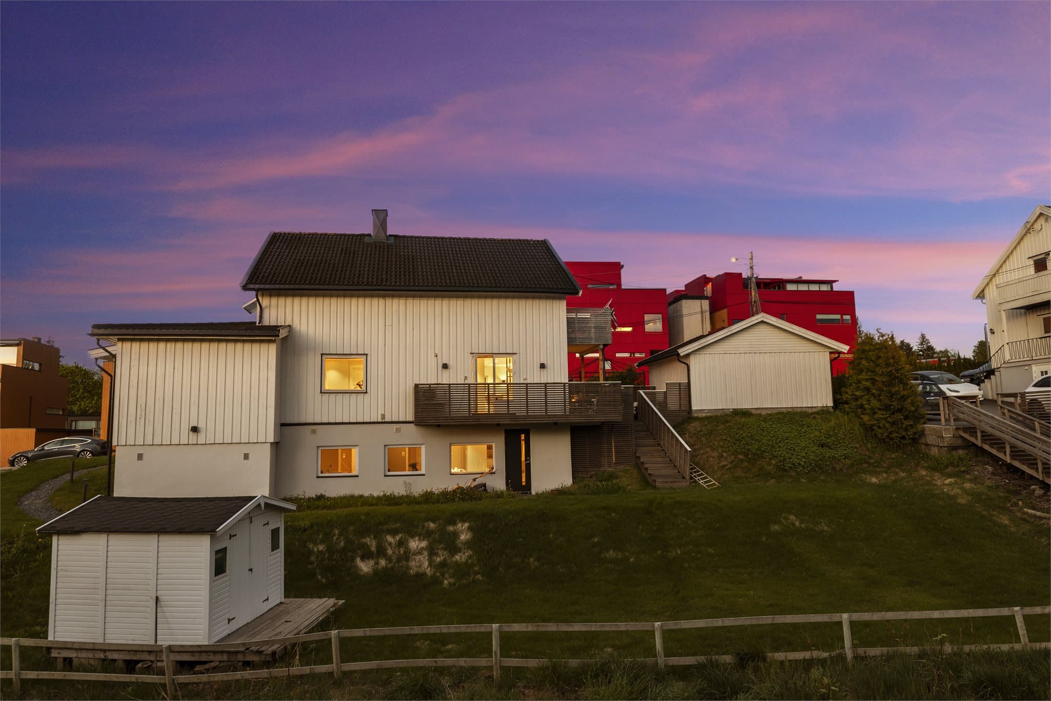 Boligens fasade med malt trepanel og tak tekket med takstein og takplater.