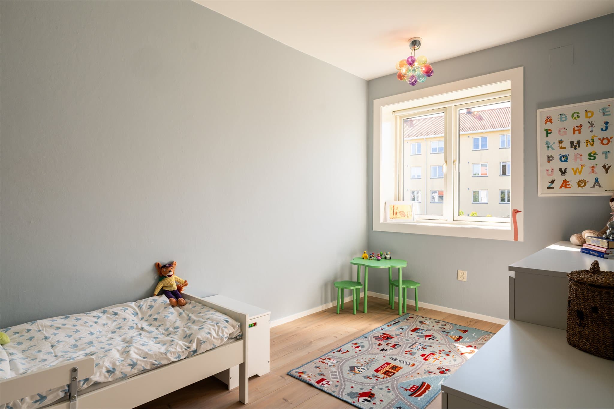 Et lyst og innbydende barnerom med god plass til både seng, oppbevaring og lek.