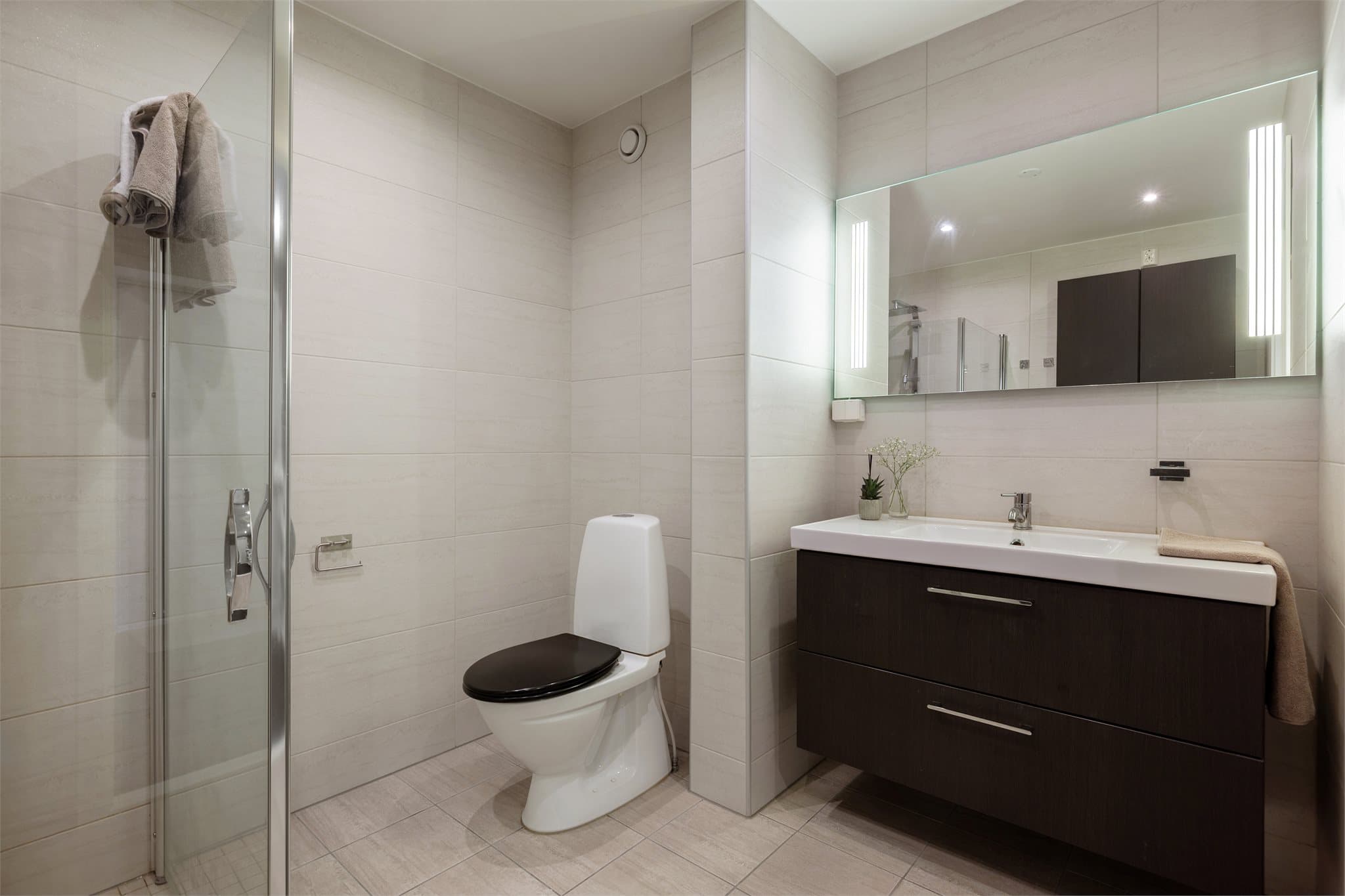 Store, lyse fliser gir badet et moderne og stilrent uttrykk. Badet ble pusset opp i 2014