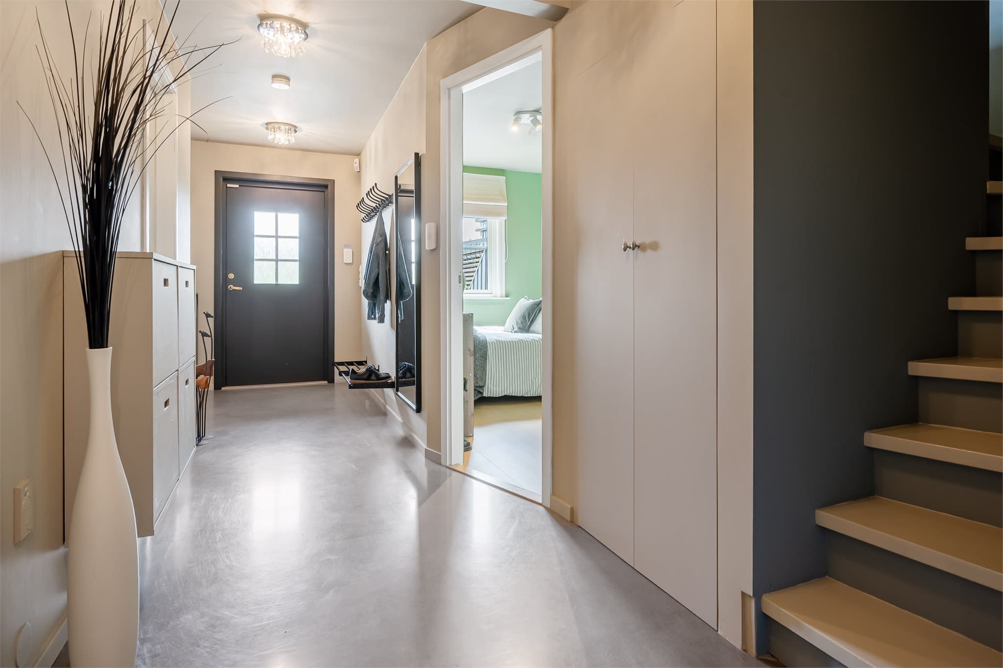 Innbydende entré med slitesterkt diamantslipt betonggulv og behagelig gulvvarme. Praktisk oppbevaring i skap og rom under tett trapp.