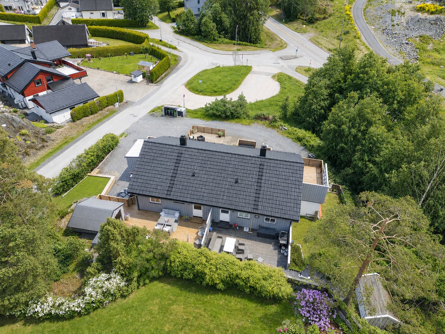 Fra luften ser man hvordan boligen kombinerer praktiske uteområder med naturtomt og skjermede oppholdssoner.