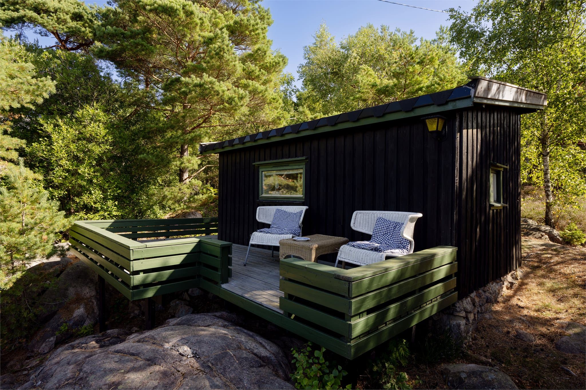 Frittliggende anneks med pulttak og tilhørende treterrasse på berget.