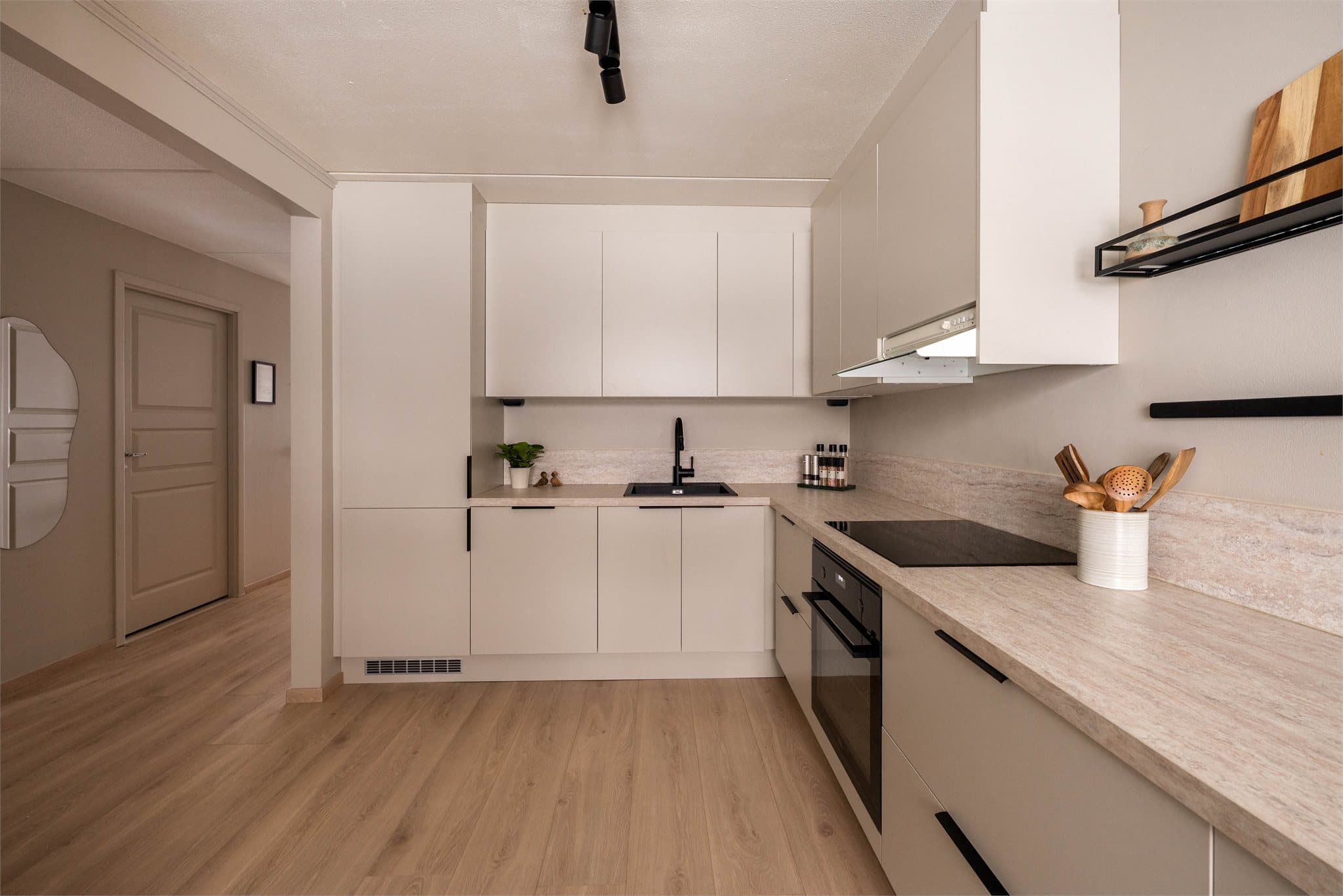 Kjøkkenet fra HTH tilbyr godt med skap- og benkeplass, og har innredning med glatte, fabrikklakkerte fronter og laminat benkeplate med nedfelt kum i kompositt.