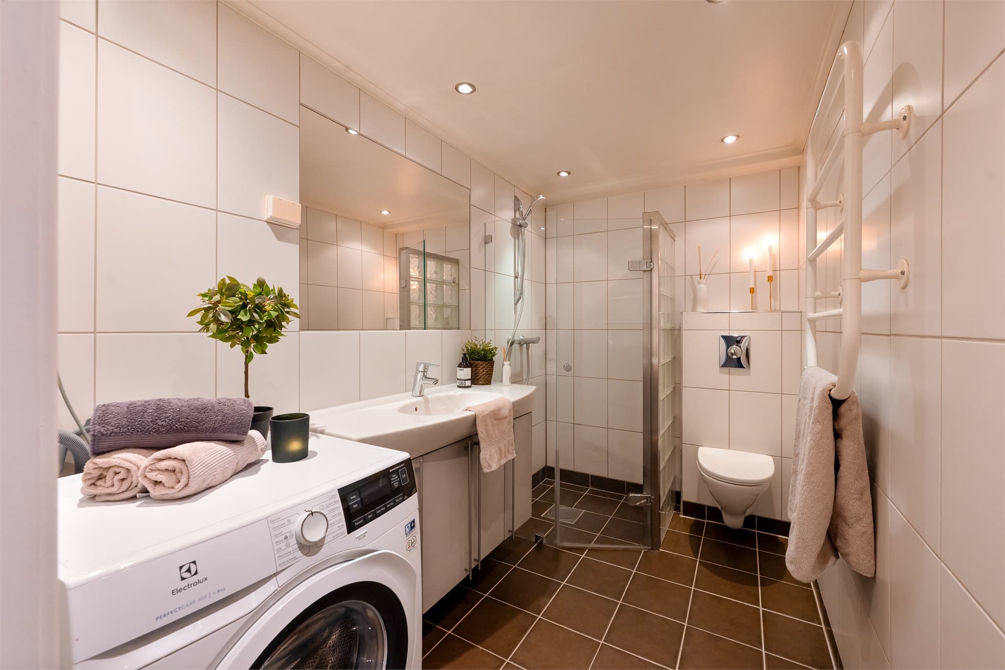 Badet er et pent, flislagt baderom fra 2005 med fliser på både gulv og vegger.