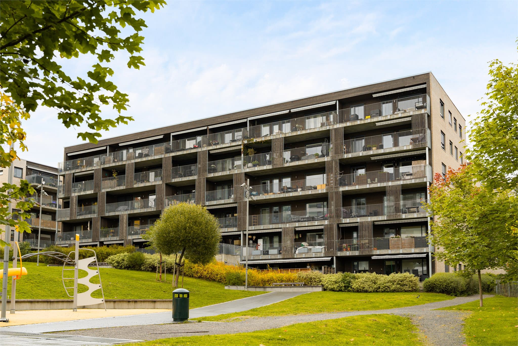Bygget har en moderne arkitektur med mørk kledning og store balkonger.