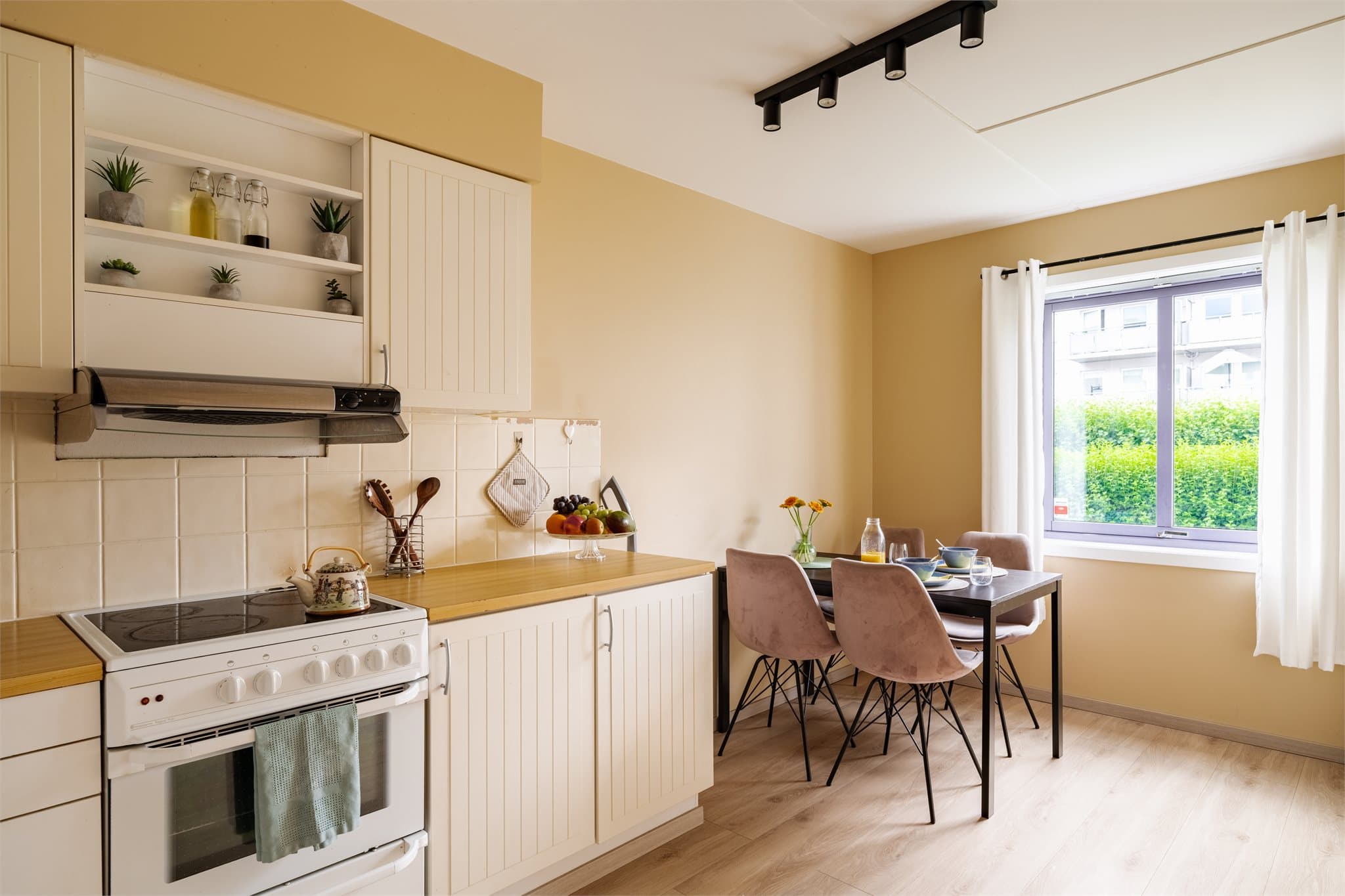 Kjøkkenet har innredning med hvite, glatte fronter og en benkeplate i laminat, som gir et rent og tidløst uttrykk.