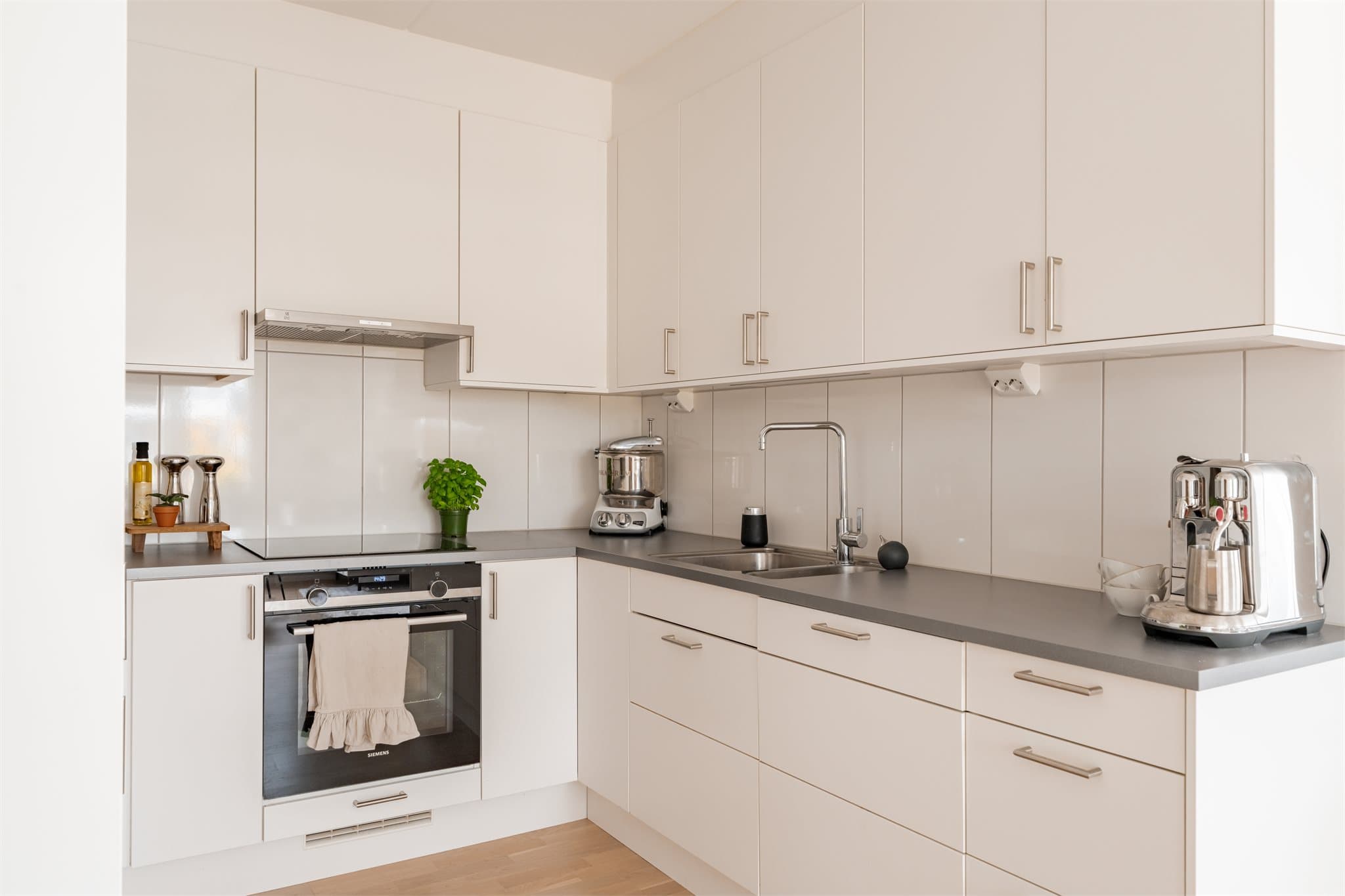 Kjøkkenet har god skap- og benkeplass, integrerte hvitevarer og et helhetlig design som passer perfekt inn i leilighetens moderne uttrykk.