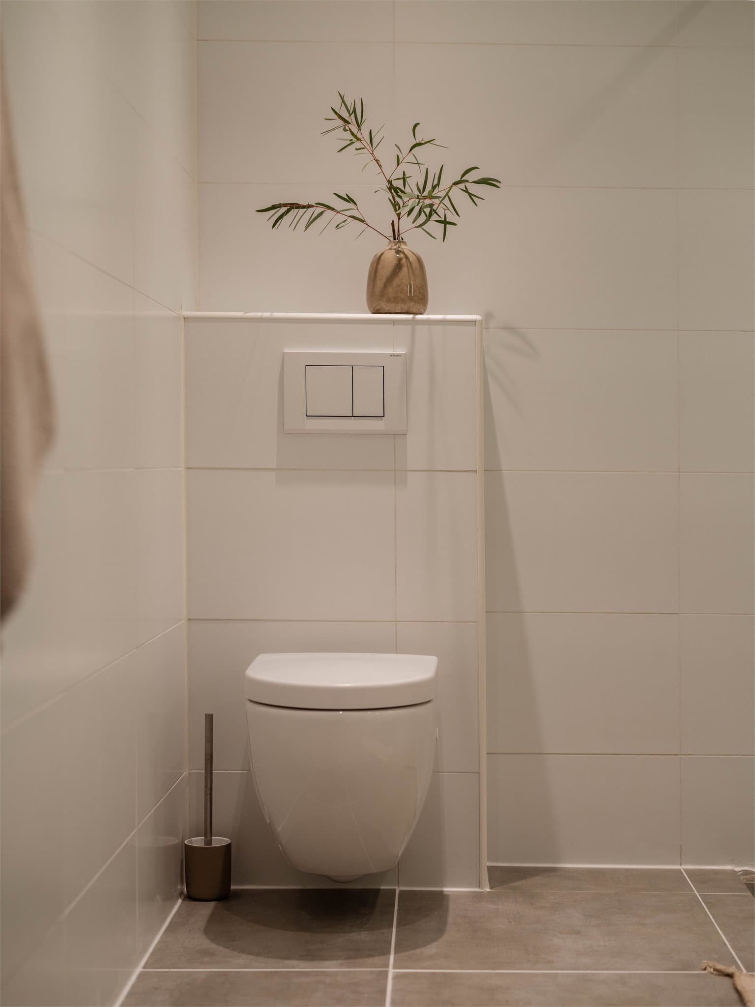 Badet har vegghengt toalett og opplegg for vaskemaskin og tørketrommel.