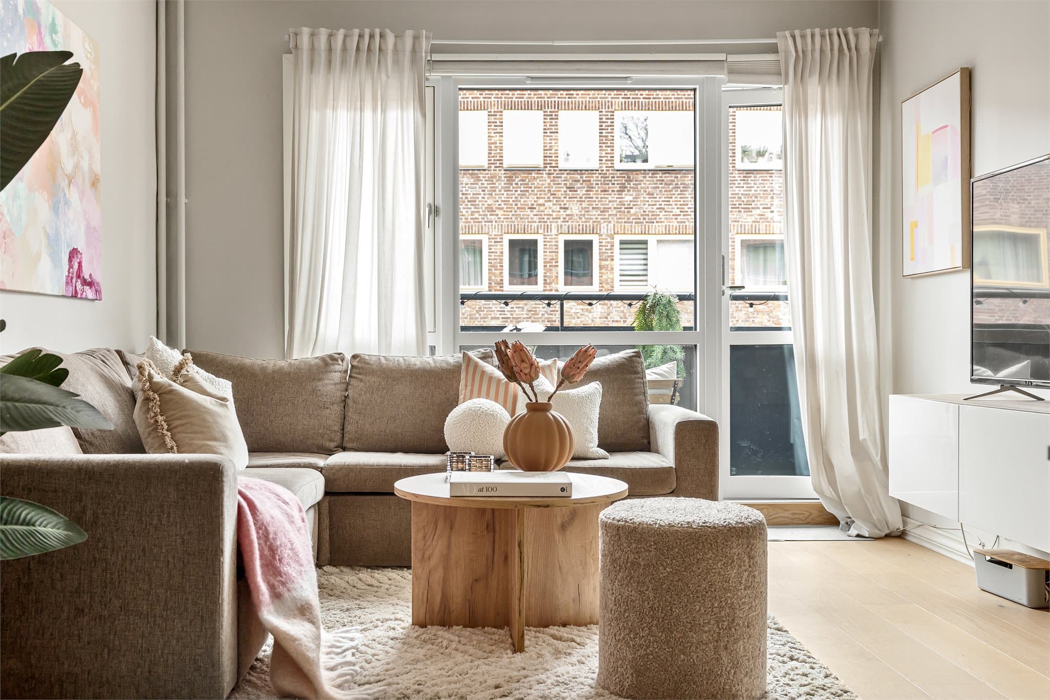 Dagslyset fra de store vinduene forsterker romfølelsen og gjør stuen til et naturlig oppholdsrom.