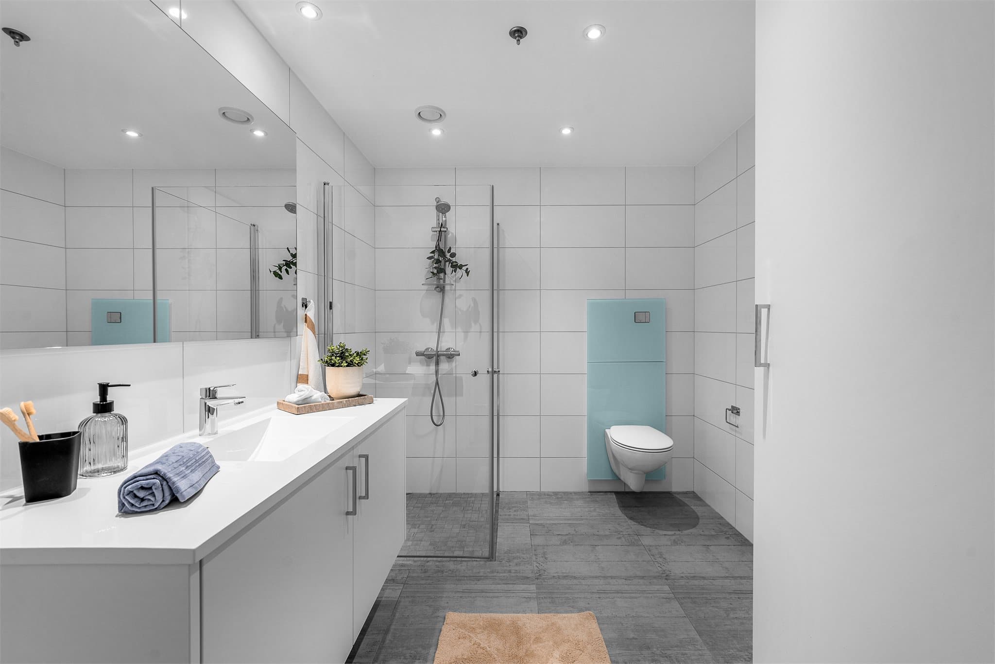 Innredning består av servantskap med nedfelt servant, underskap og 1-greps blandebatteri. Dusjhjørne med glassdører, opplegg for vaskemaskin og vegghengt toalett.